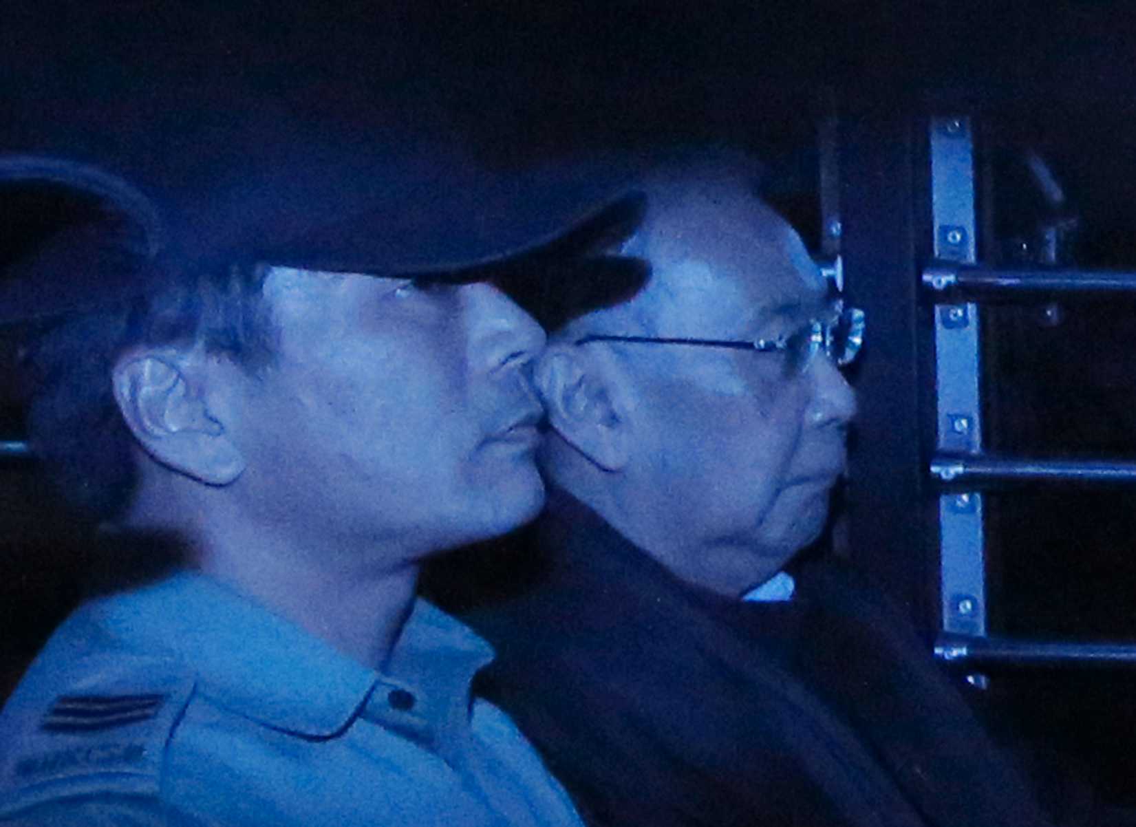 In this photo taken through a tinted glass, former Hong Kong Chief Secretary Rafael Hui, right, is escorted by a staff member from Hong Kong Correctional Services inside a van outside the High Court in Hong Kong on Dec. 19, 2014