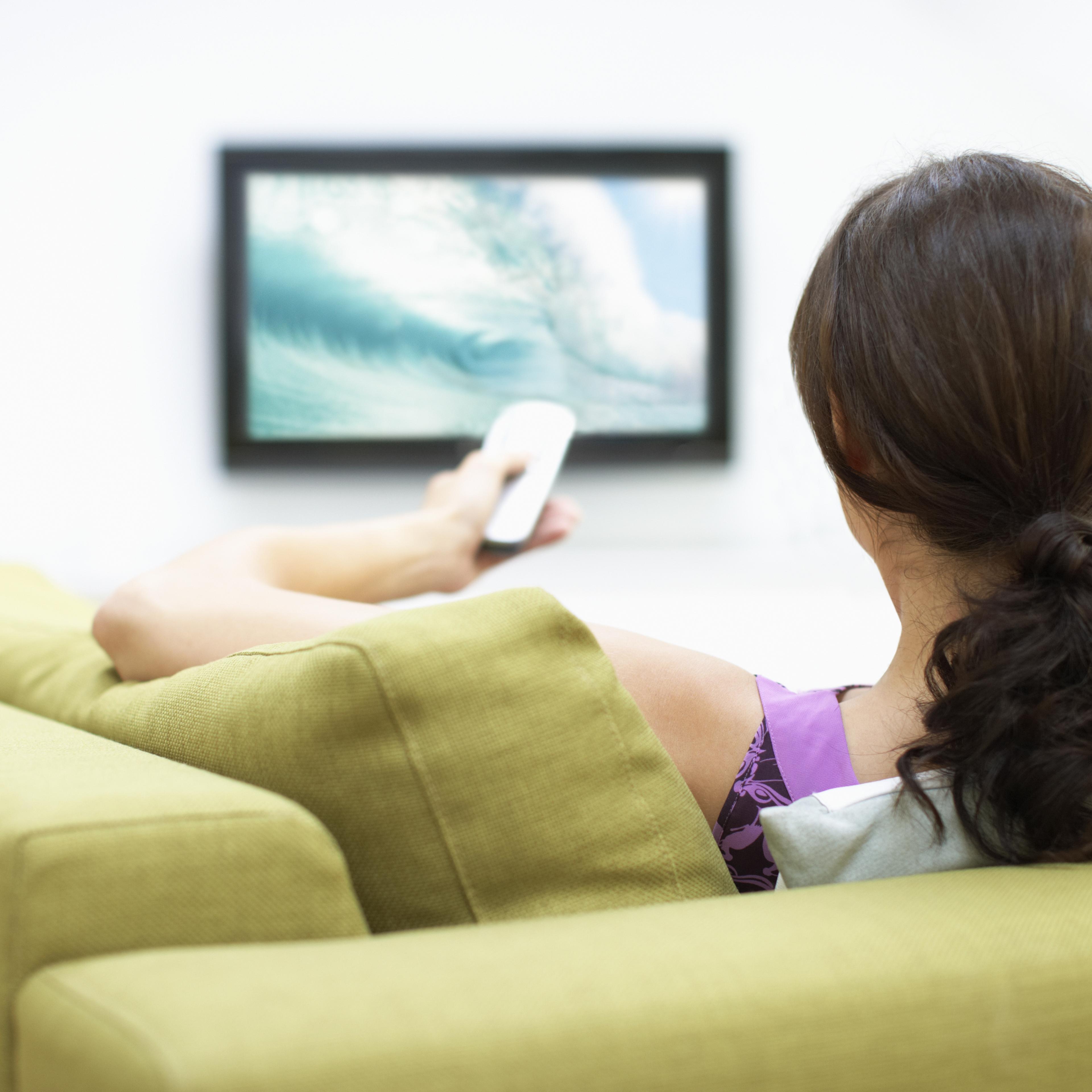 Young woman watching television, rear view