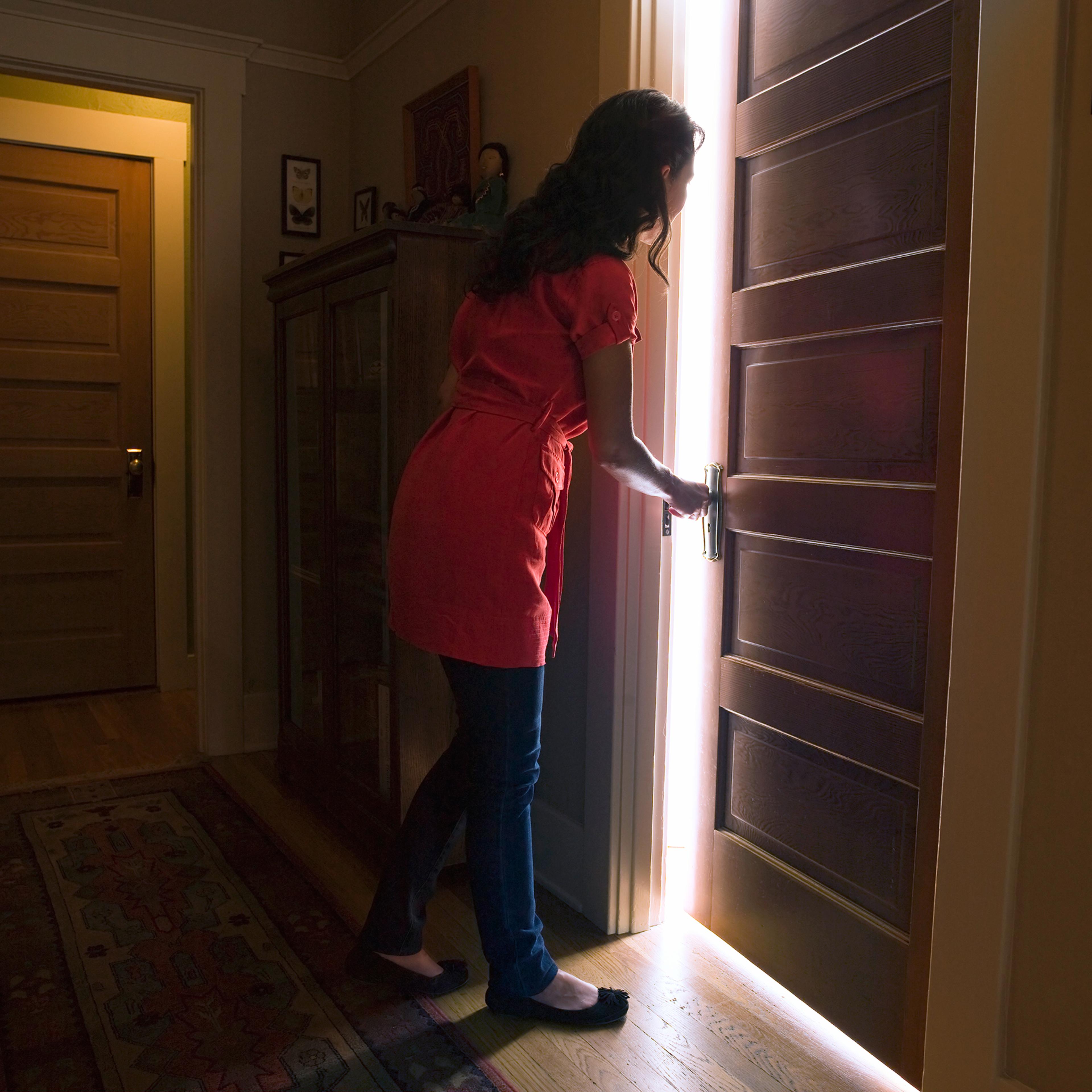 Woman opening bedroom door with light coming out