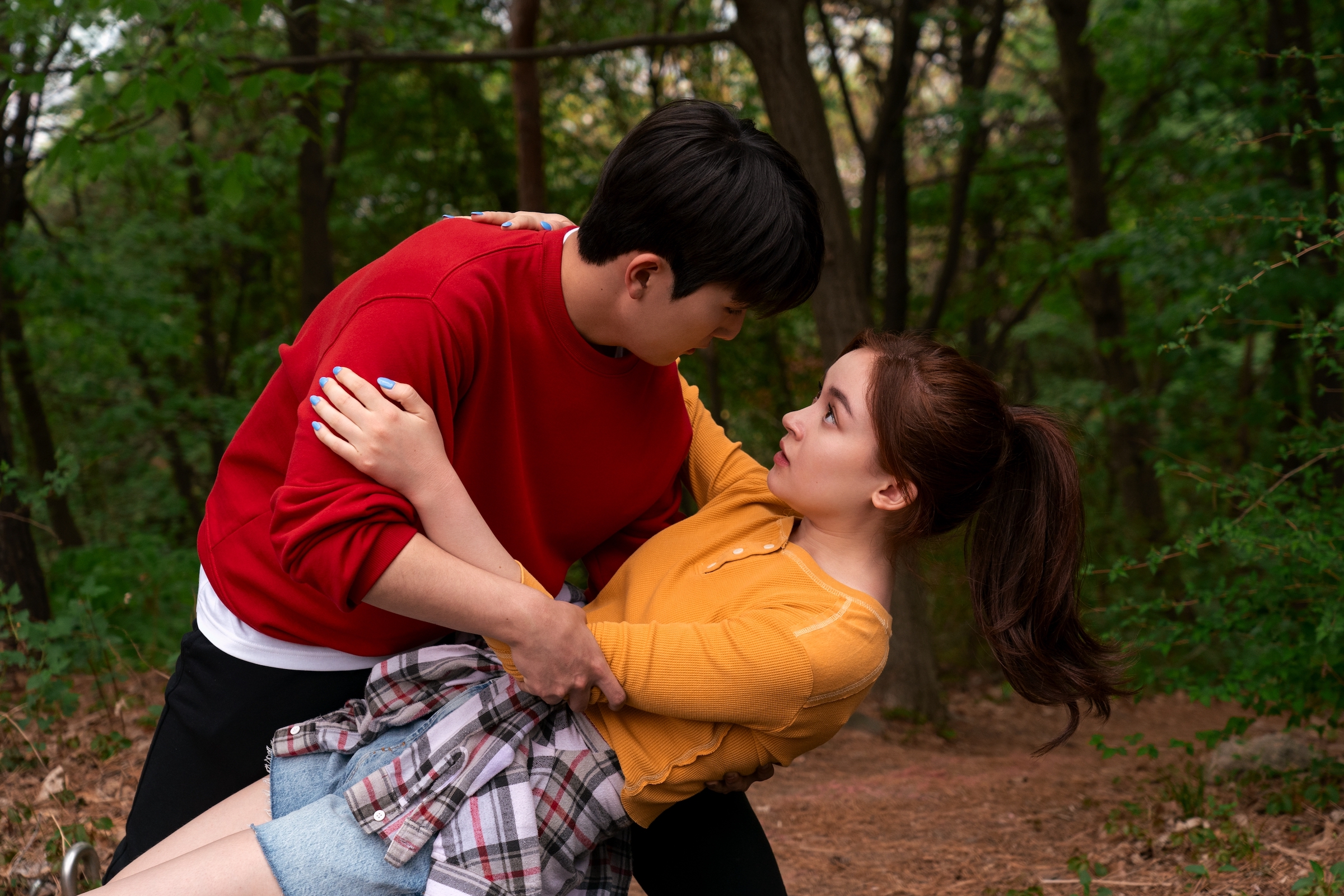 Kitty (Anna Cathcart) trips on a hike and Dae (Choi Min-yeong) catches her.