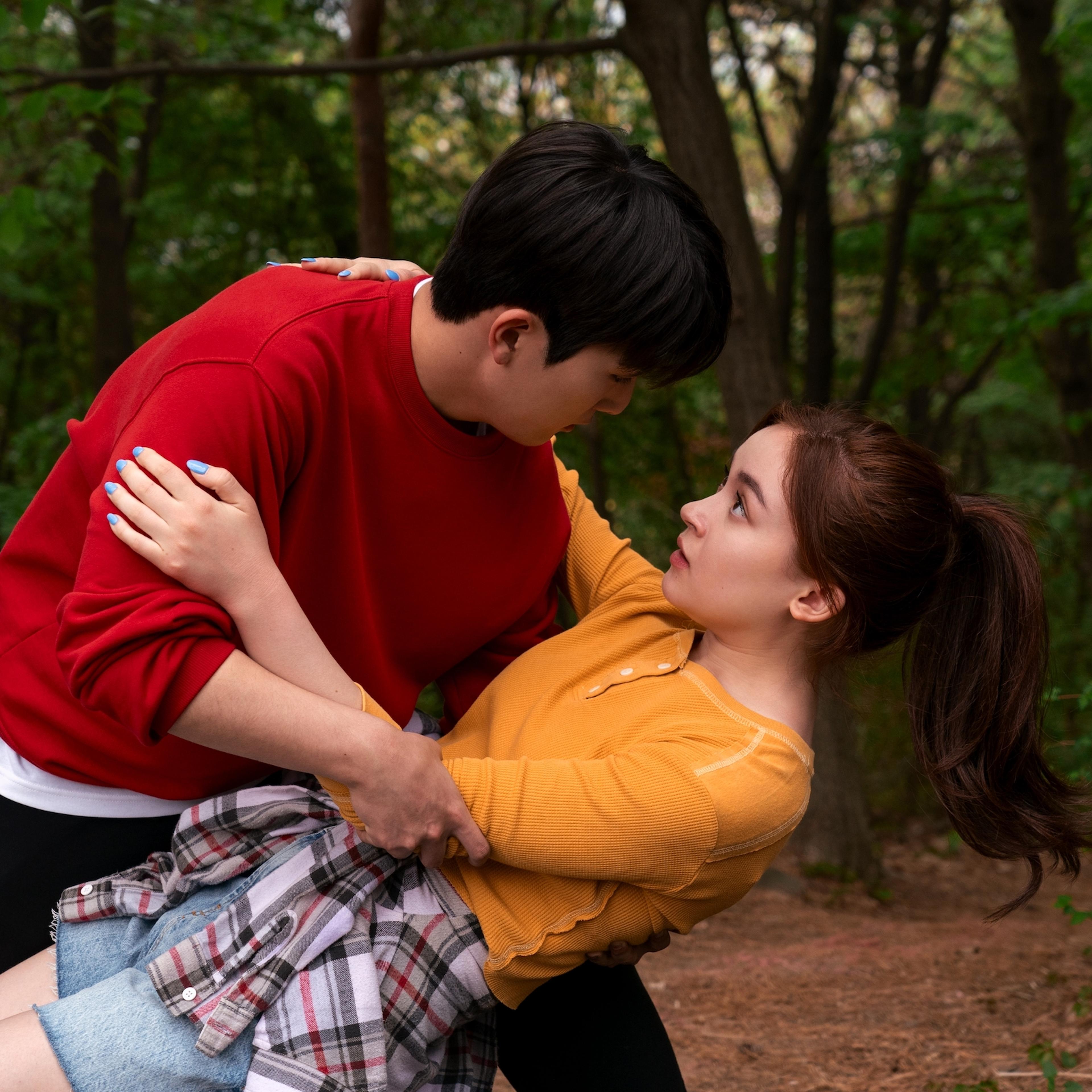Kitty (Anna Cathcart) trips on a hike and Dae (Choi Min-yeong) catches her.