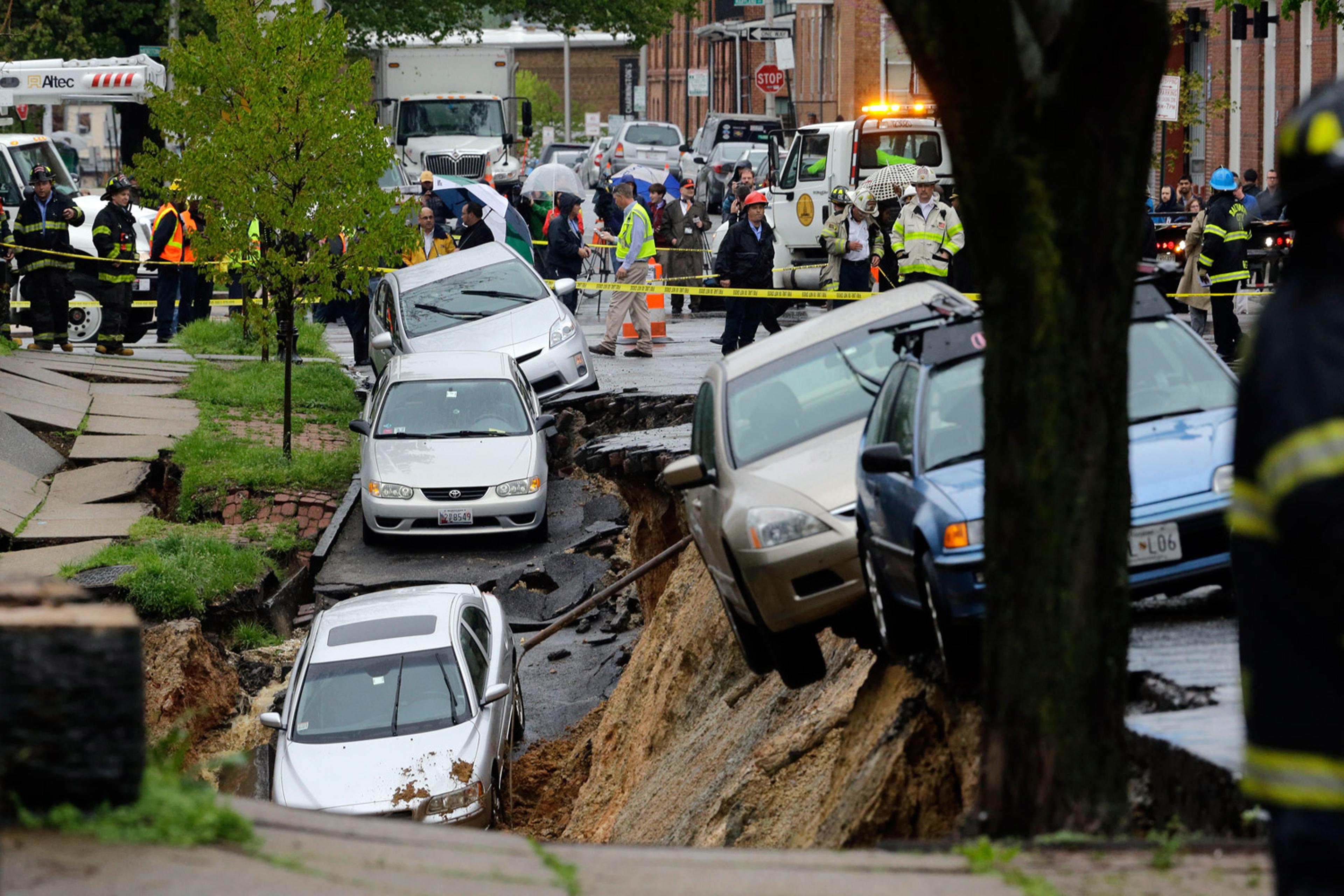 Cars sit on the edge of a sinkhole in the Charles Village neighborhood of Baltimore, April 30, 2014, as heavy rain moves through the region.