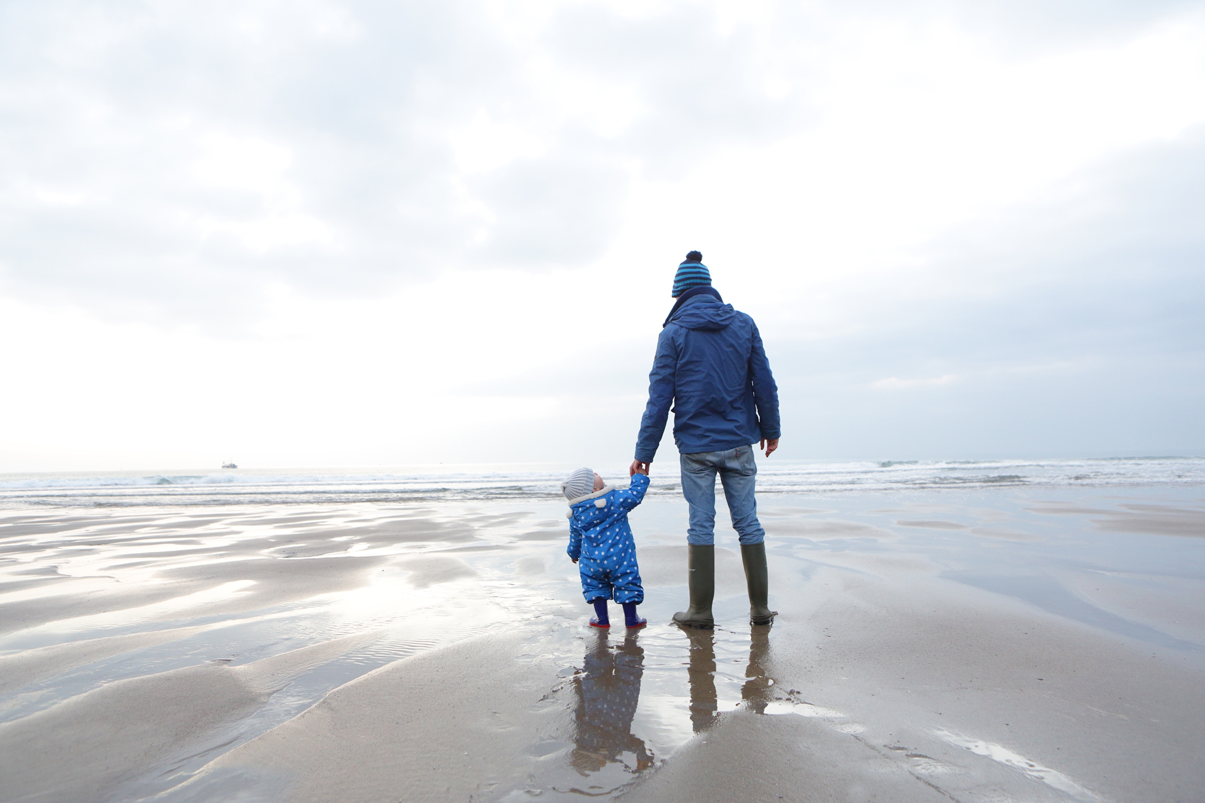 father and child on the beach , child looks up .