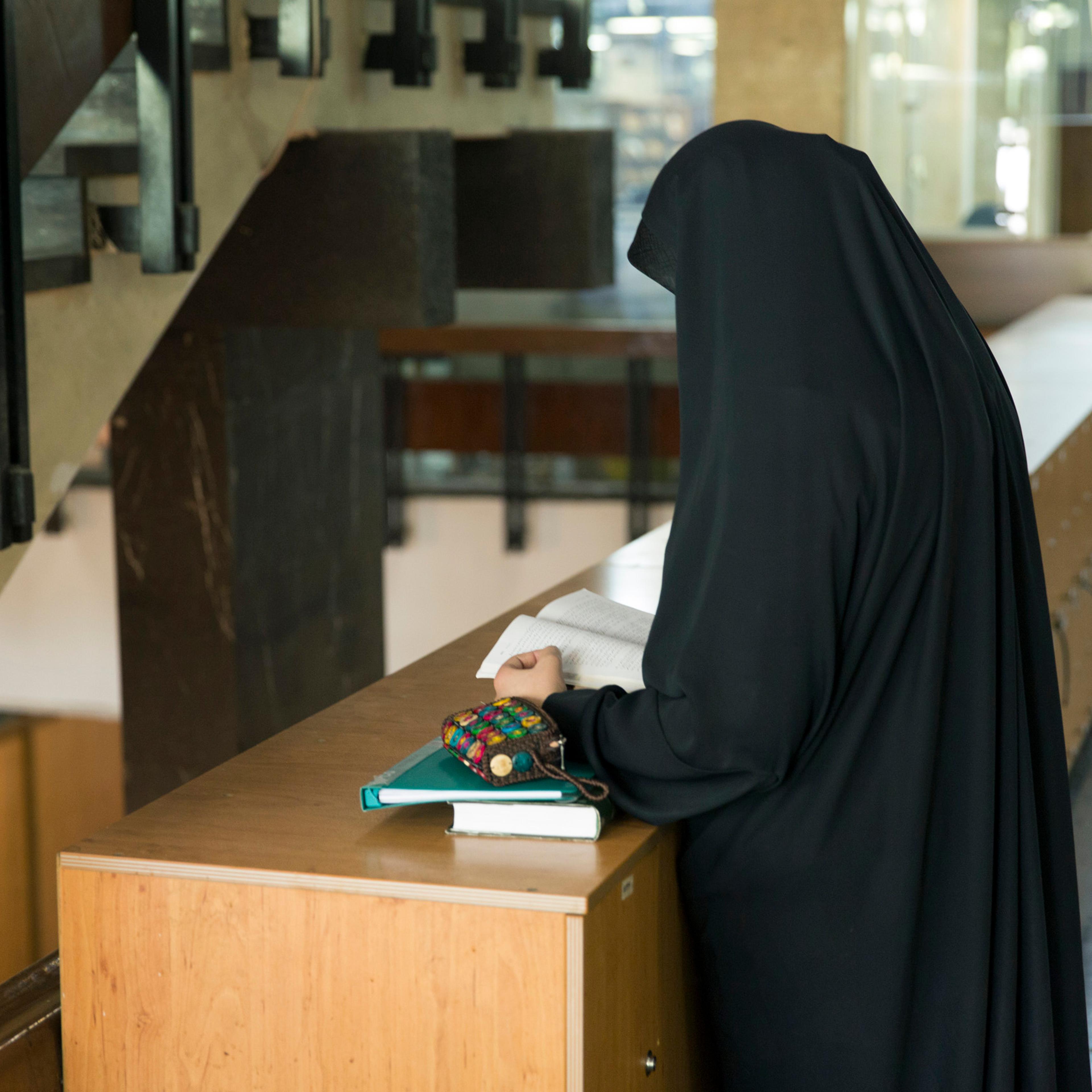 A veiled female student reading a book at the University of Tehran on October 18, 2015.