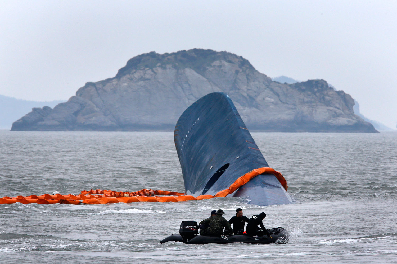 A dinghy involved in salvage operations passes near the upturned South Korean ferry <i>Sewol</i> in the sea off Jindo, South Korea, on April 17, 2014
