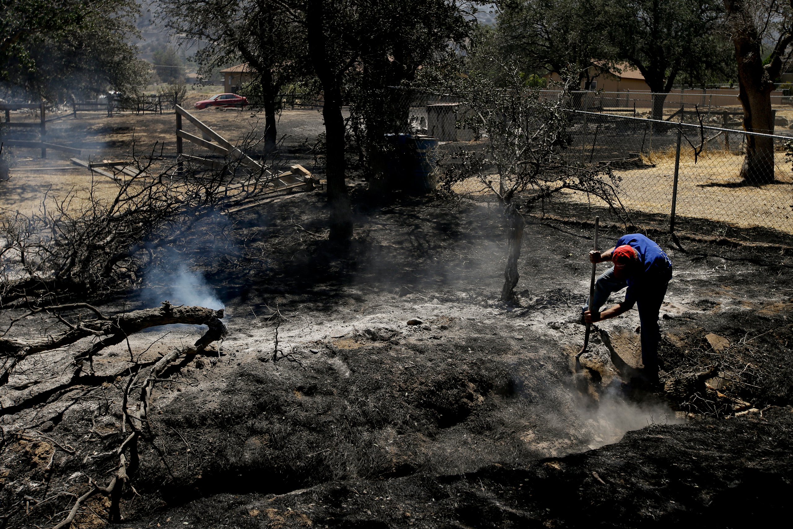 Alan Germain puts out hotspots on his neighbor's property destroyed by a wildfire Friday, June 24, 2016, near Lake Isabella, Calif. The wildfire that roared across dry brush and trees in the mountains of central California gave residents little time to f