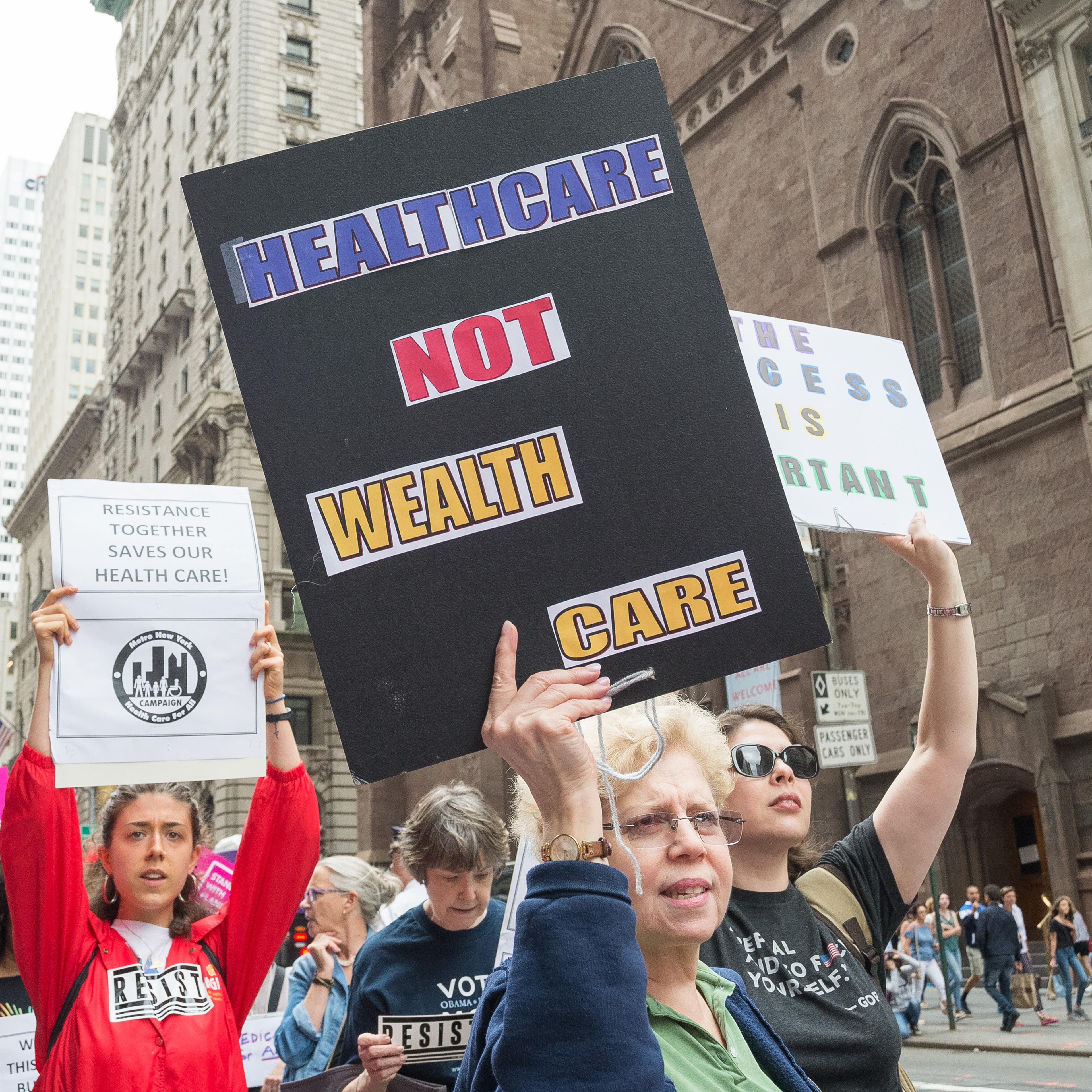 Participants hold signs while protesting the repeal and