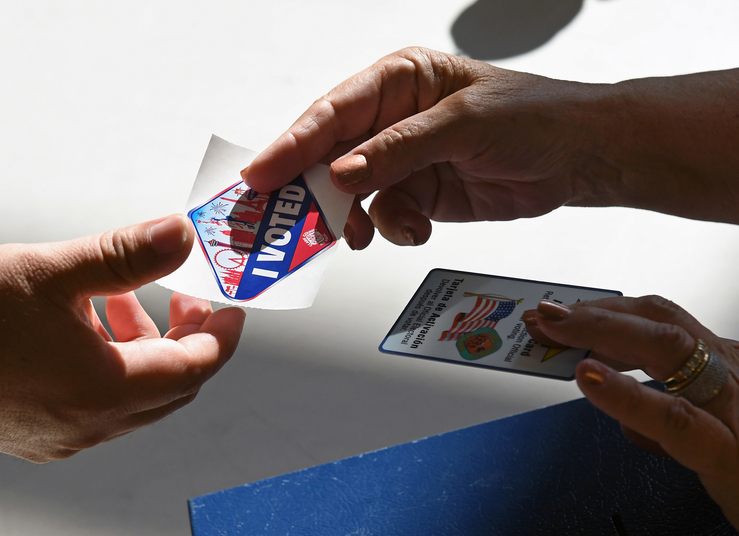 A poll worker gives a voter a Las Vegas Strip-themed "I Voted" sticker after taking back her voter activation card at a polling station at Cheyenne High School on Nov. 8, 2016.