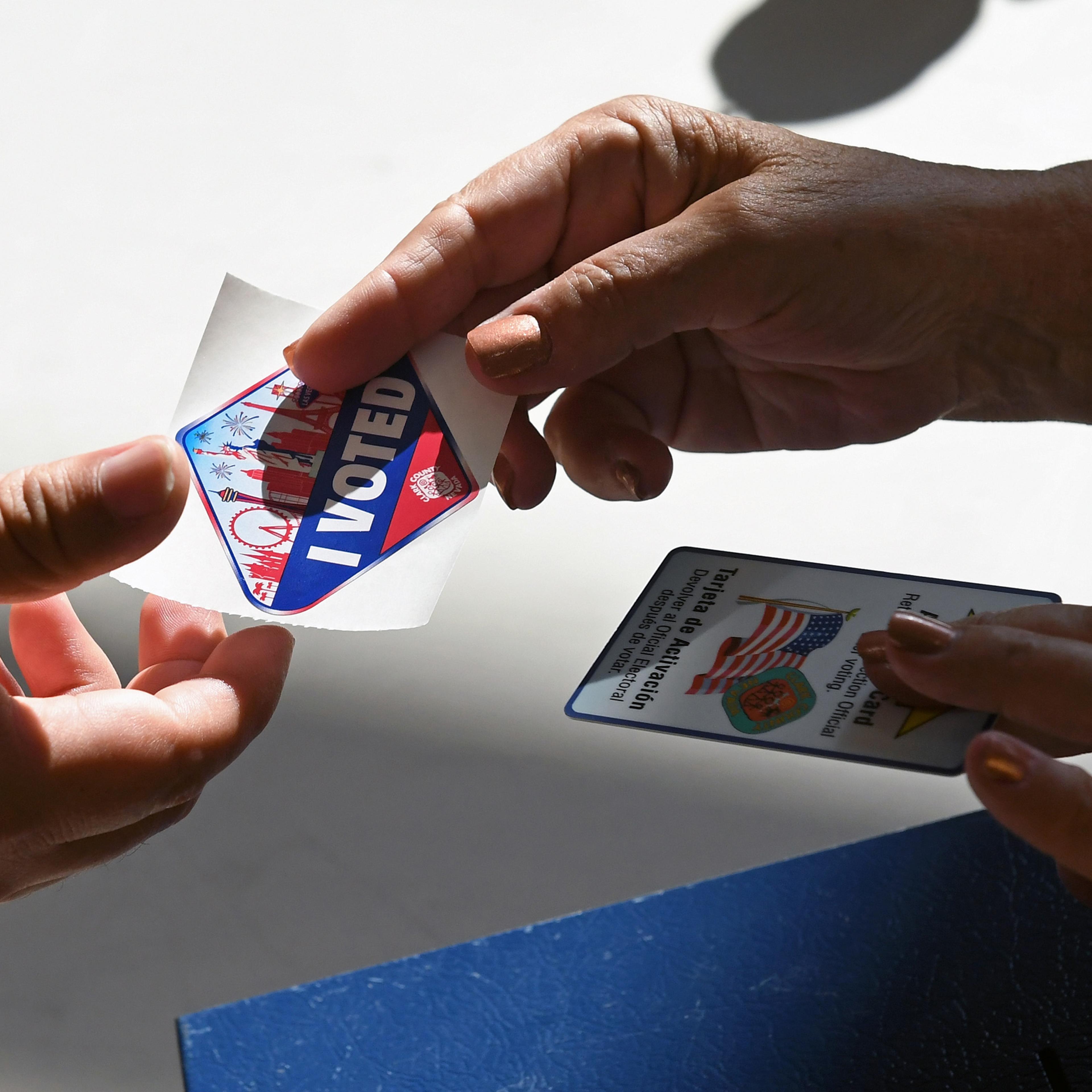 A poll worker gives a voter a Las Vegas Strip-themed "I Voted" sticker after taking back her voter activation card at a polling station at Cheyenne High School on Nov. 8, 2016.