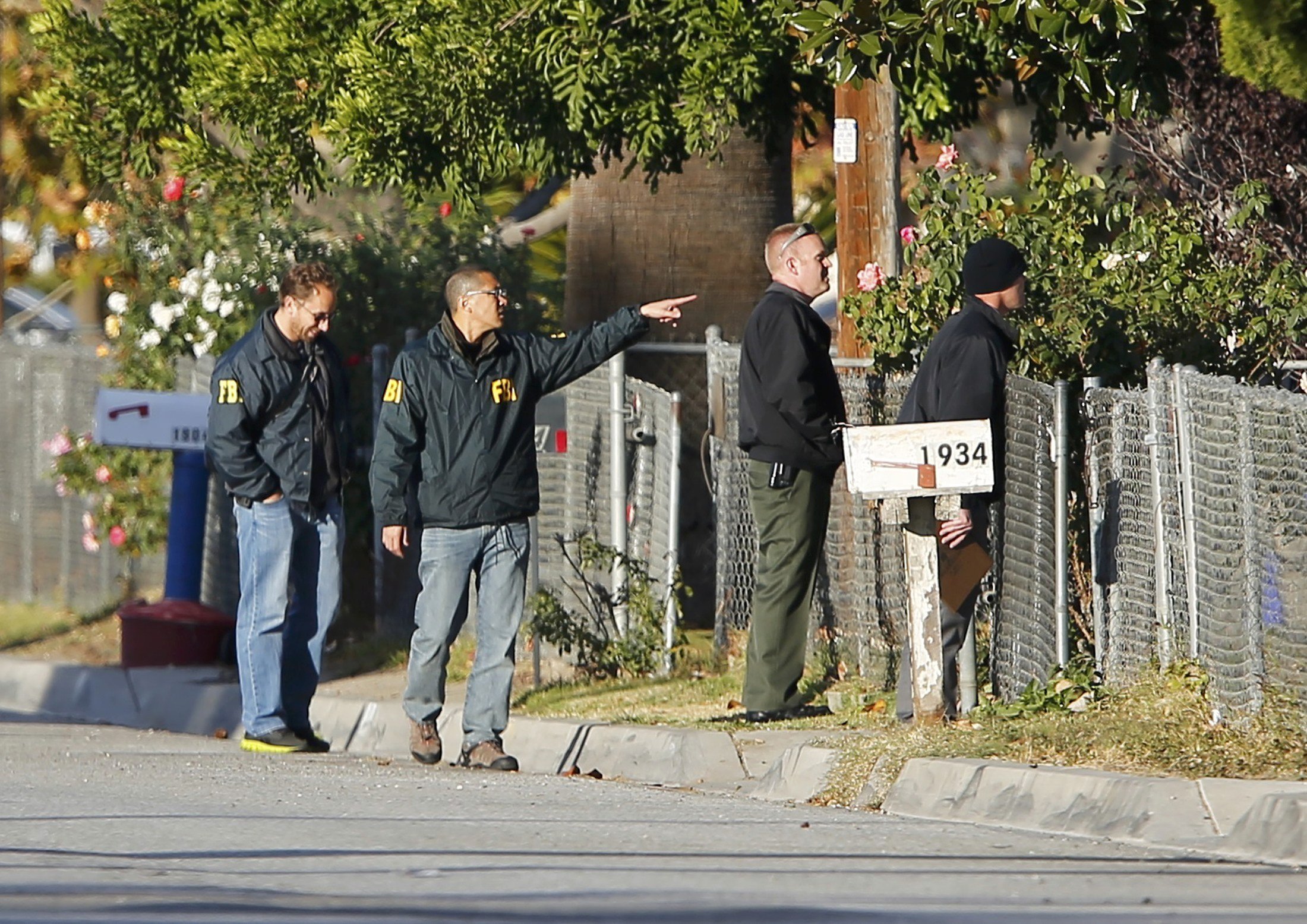 FBI and police continue their investigation in the neighborhood near the SUV vehicle in which two suspects were shot following a mass shooting in San Bernardino, Calif. on Dec. 3, 2015.