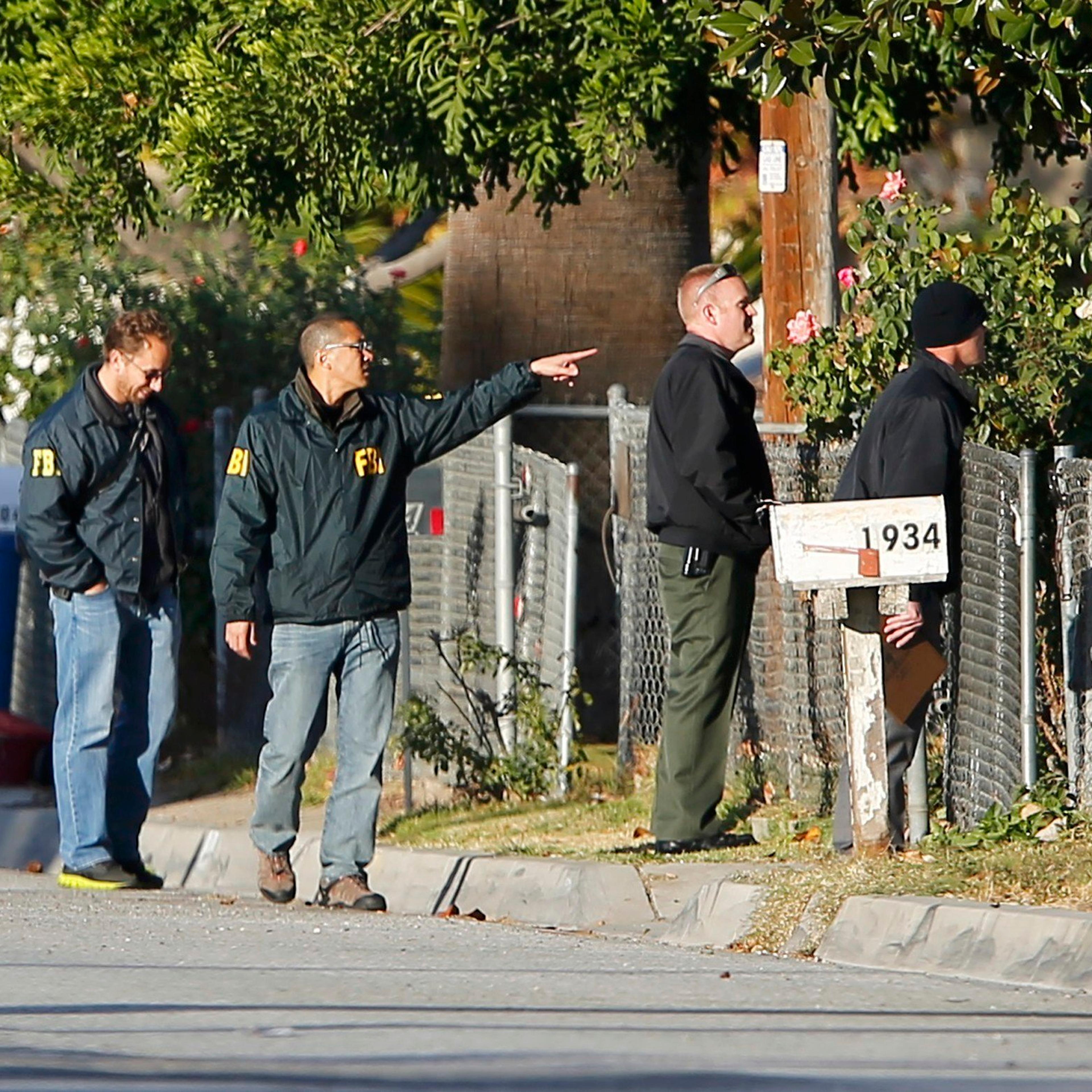 FBI and police continue their investigation in the neighborhood near the SUV vehicle in which two suspects were shot following a mass shooting in San Bernardino, Calif. on Dec. 3, 2015.