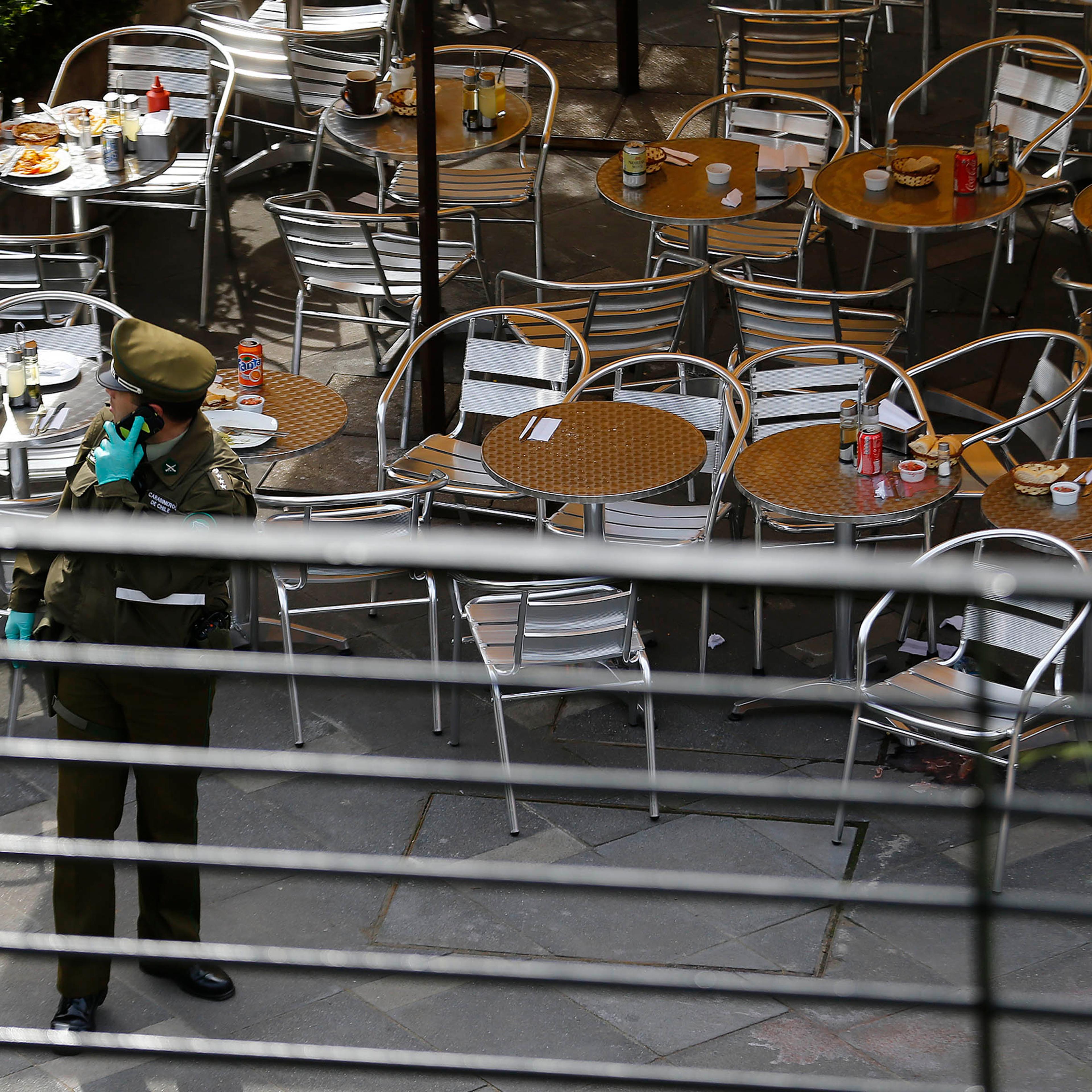 A police officer talks on his cell phone at the area where a bomb exploded in Santiago