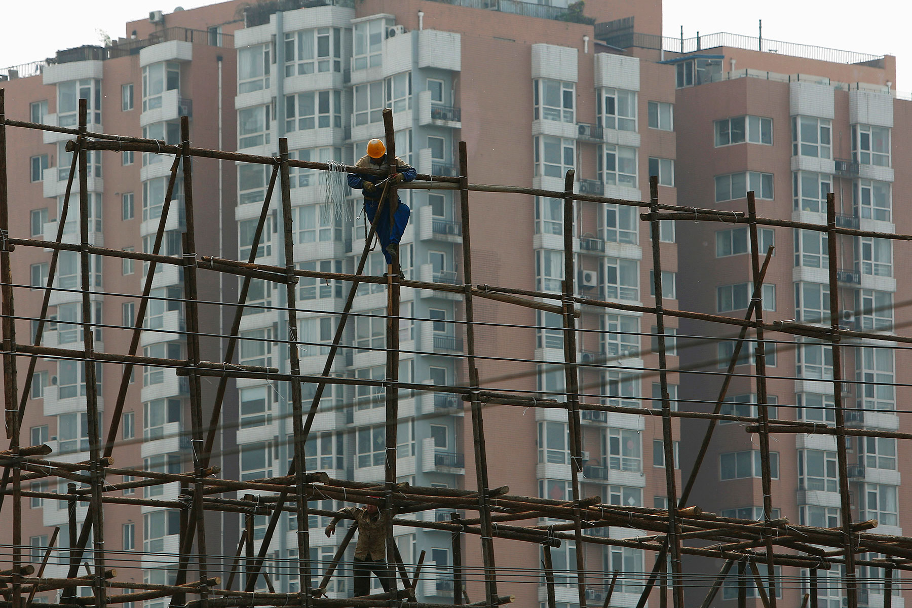A laborer works on the scaffolding of a construction site for a new residential building in Beijing on May 8, 2014