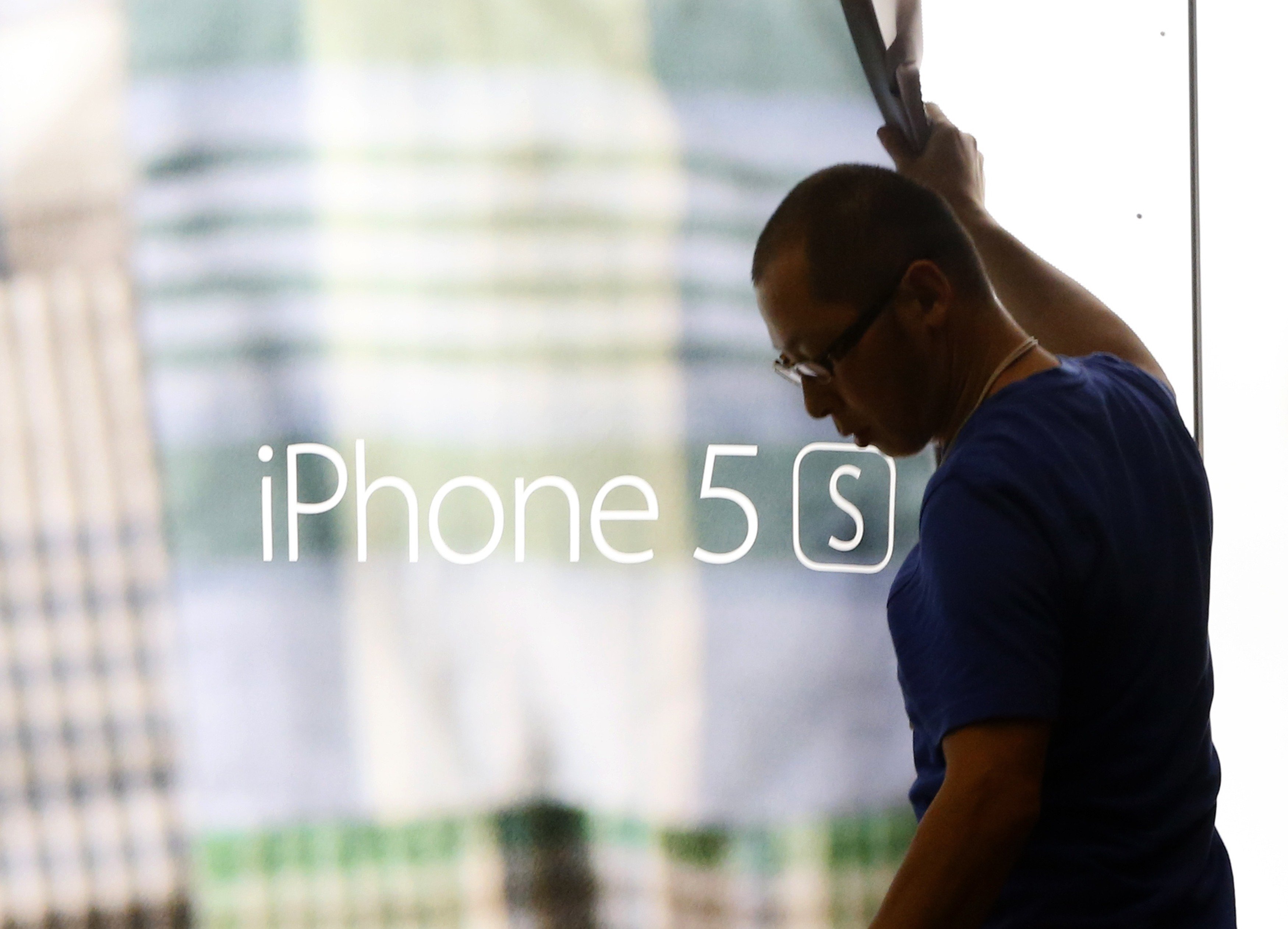 A staff member removes a display poster of iPhone 5S at the Apple store in Tokyo on Sept. 18, 2014,.