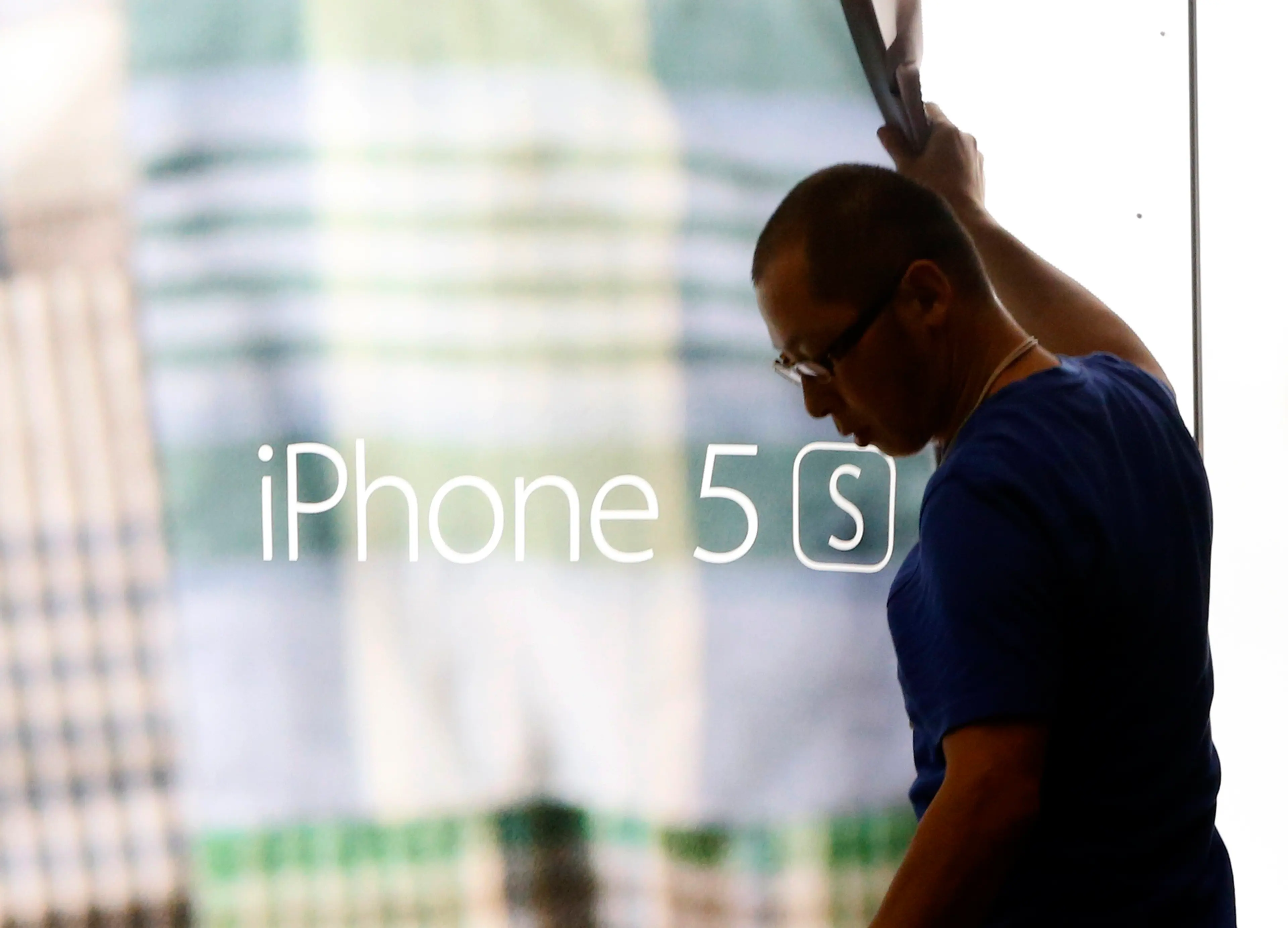 A staff member removes a display poster of iPhone 5S at the Apple store in Tokyo on Sept. 18, 2014,.