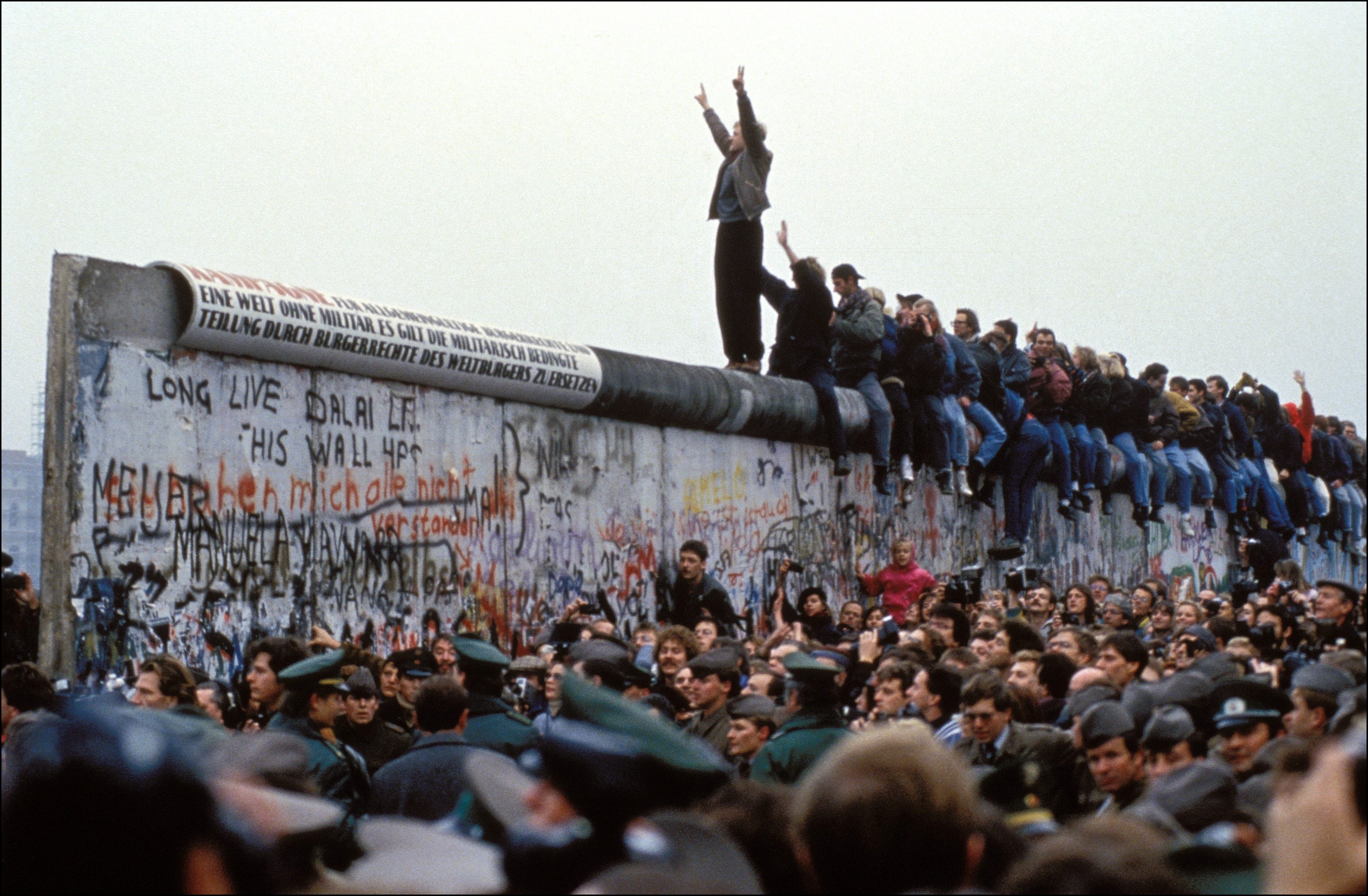 A man celebrates on the Berlin wall on November 12, 1989 in Berlin, Germany.