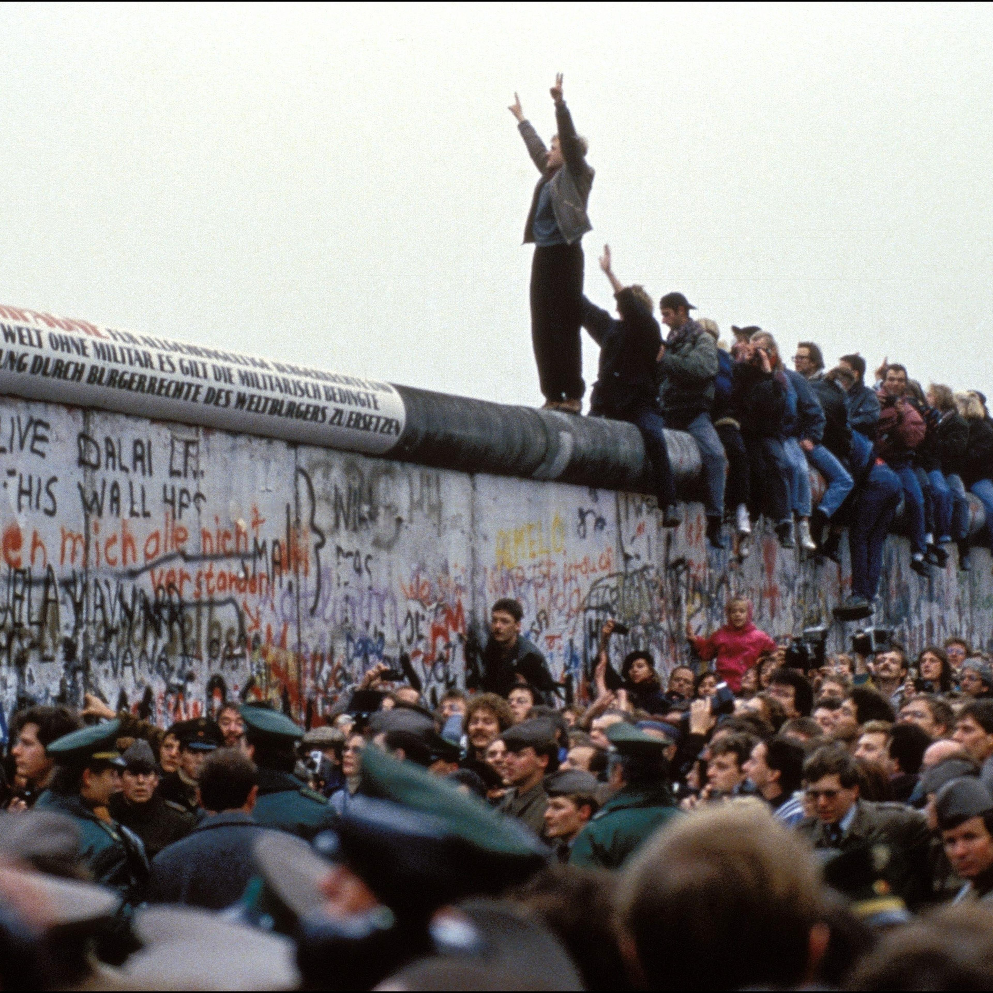 A man celebrates on the Berlin wall on November 12, 1989 in Berlin, Germany.