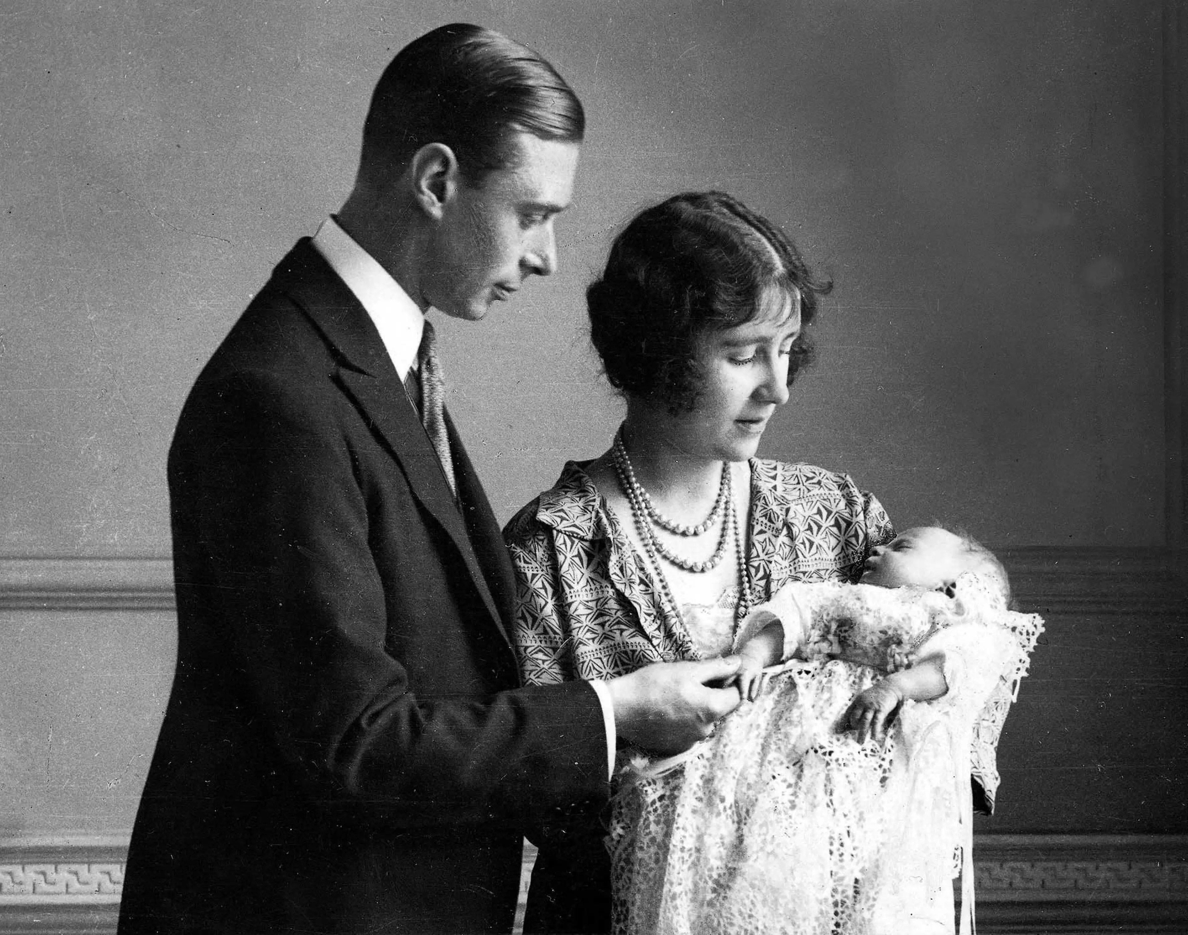 1926. The Duke and Duchess of York (later King George VI and Queen Elizabeth, the Queen Mother) pictured with their daughter (later, Queen Elizabeth II) as she sleeps in a precious christening robe, which has been used in the Royal Family for generations