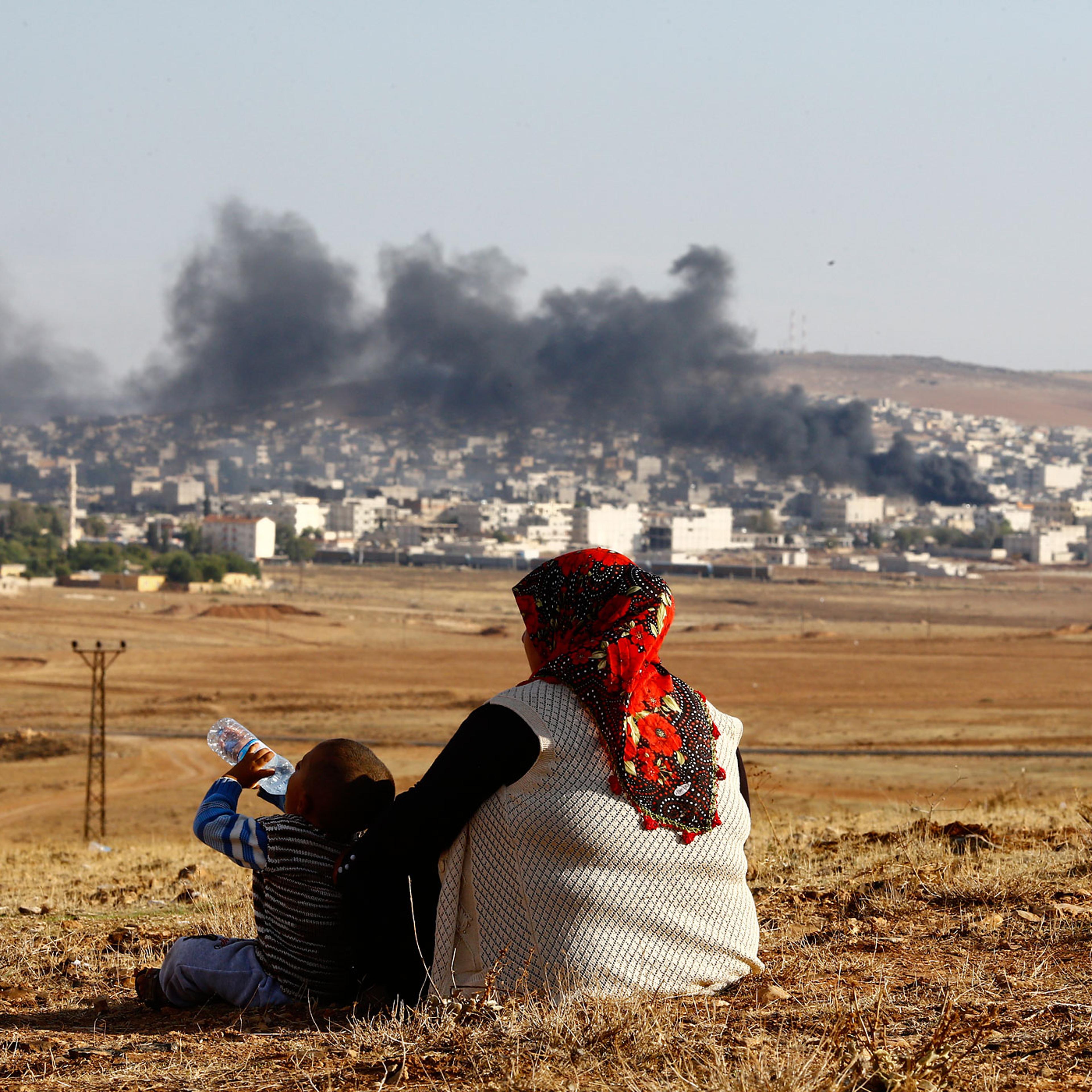 Turkish Kurds watch smoke rises over Syrian town of Kobani after an airstrike, as seen from the Mursitpinar border crossing on the Turkish-Syrian border