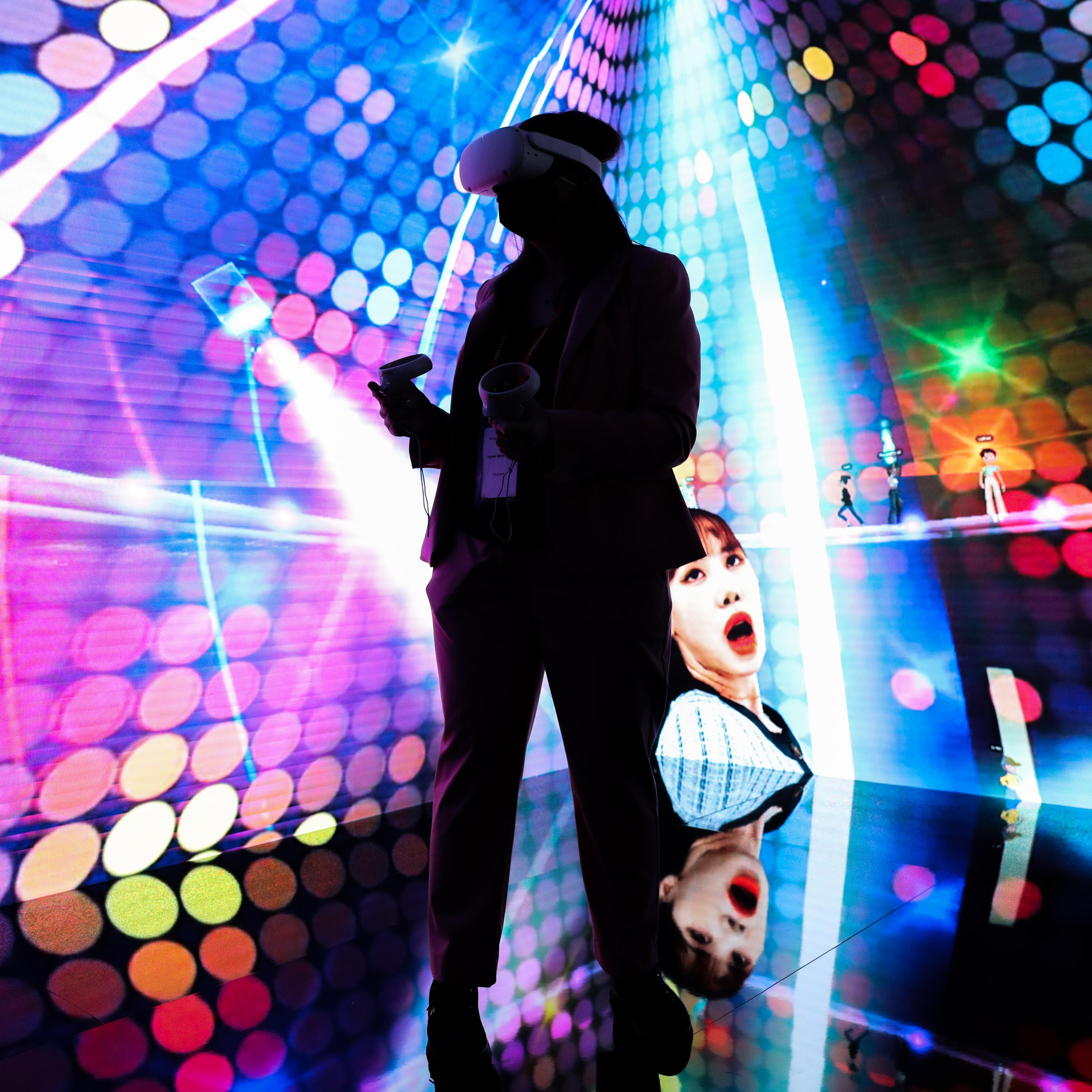 A woman wearing a virtual reality headset takes part in a metaverse concert experience at MWC Barcelona conference in Barcelona, Spain on Feb. 28, 2022.