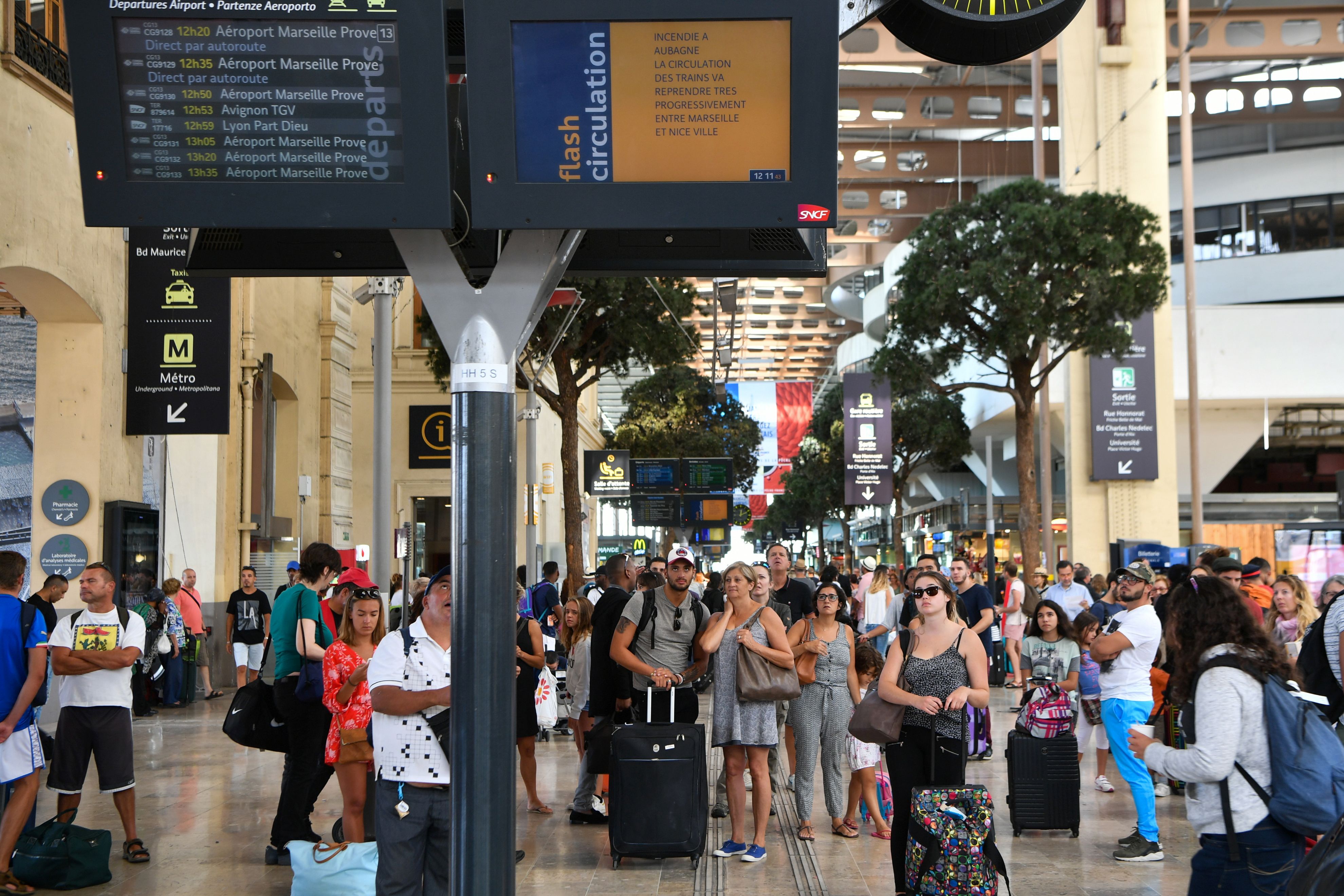 Passengers look at information monitors as they wait for their trains at The Saint-Charles Station in Marseille on Aug. 20, 2017.