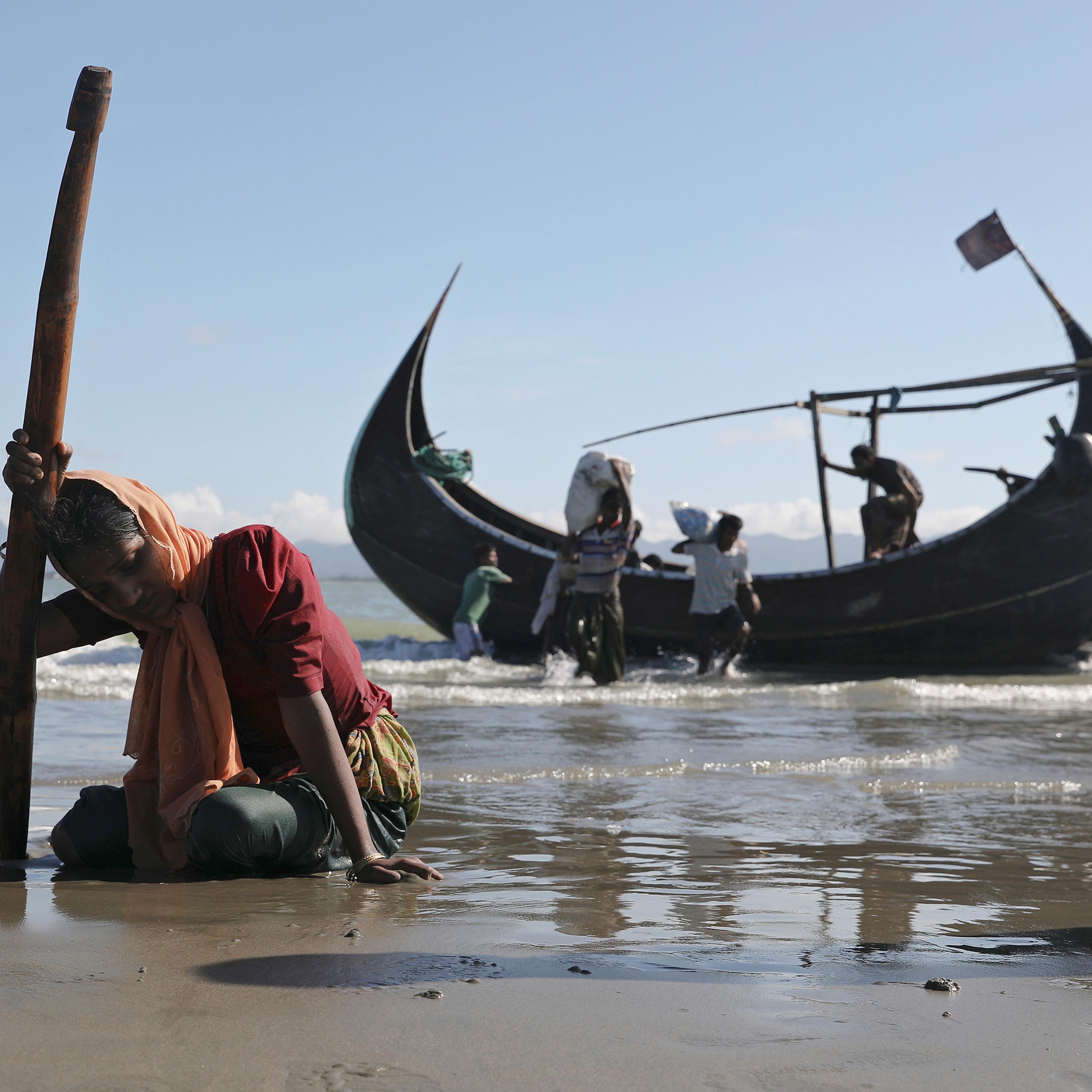 A woman collapses from exhaustion as Rohingya refugees arrive by a wooden boat from Myanmar to the shore of Shah Porir Dwip