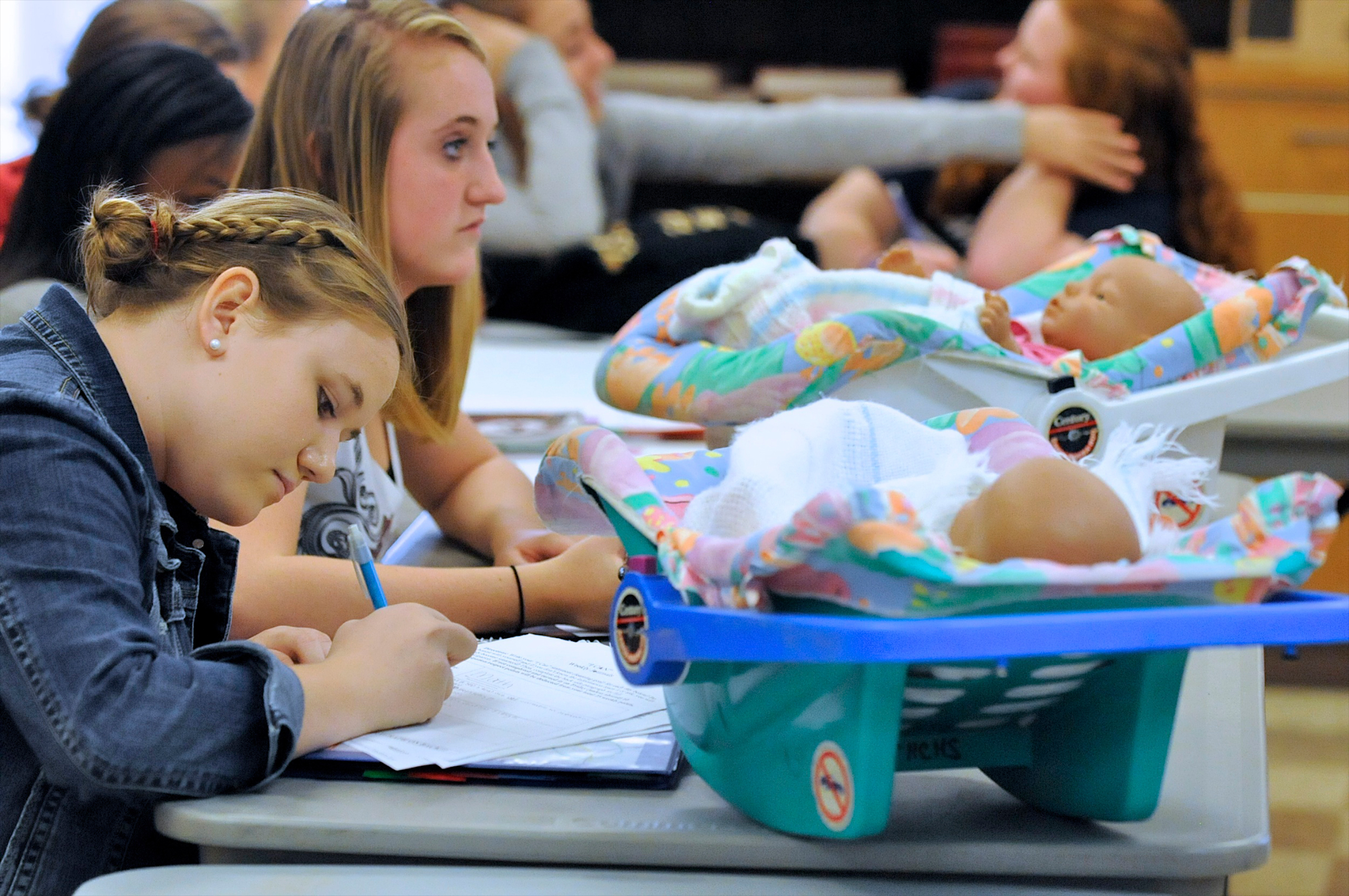 Students Sallie Norman, left, and Katie Osborne, in Catherine Gray's Child Development class, at Henderson County High, work in class with two infant simulators, in Henderson, Ky., Thursday, Oct. 6, 2011. The simulators, that students take home on weeken