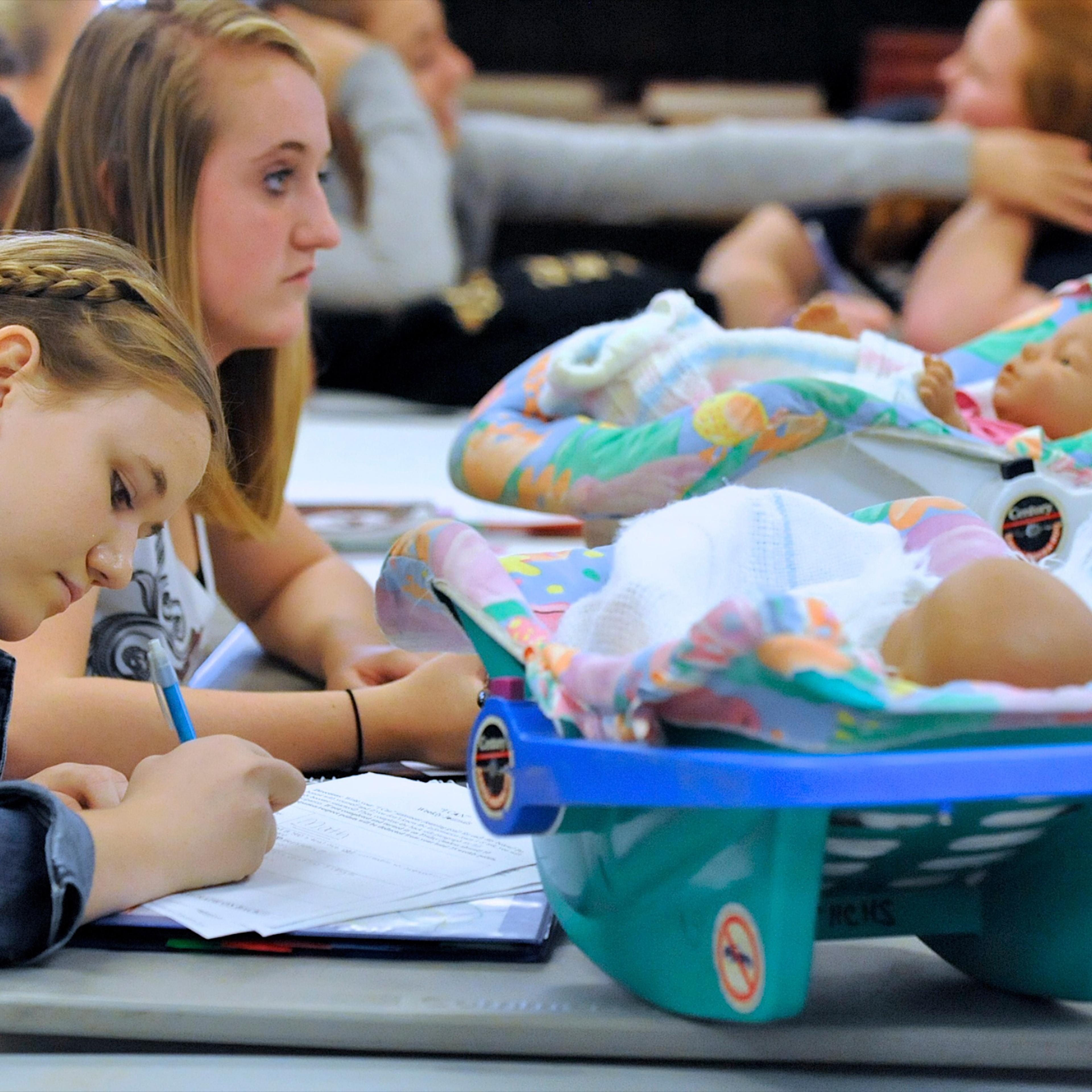 Students Sallie Norman, left, and Katie Osborne, in Catherine Gray's Child Development class, at Henderson County High, work in class with two infant simulators, in Henderson, Ky., Thursday, Oct. 6, 2011. The simulators, that students take home on weeken
