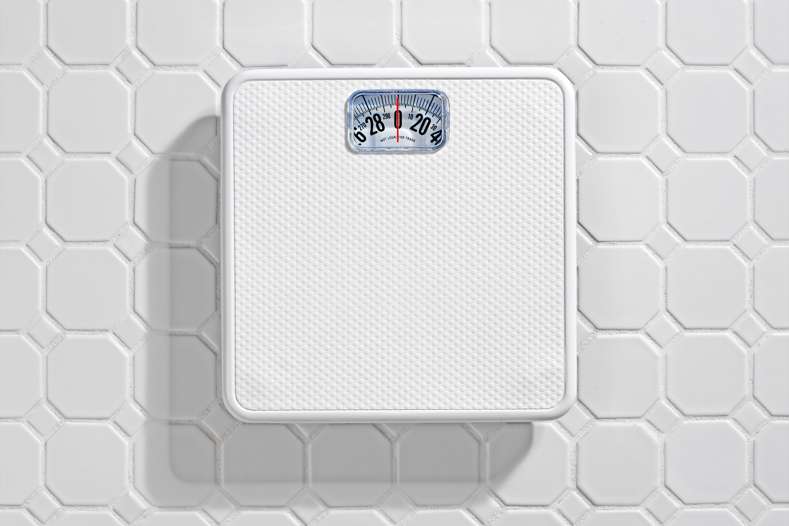 Bathroom scale on white tile floor.