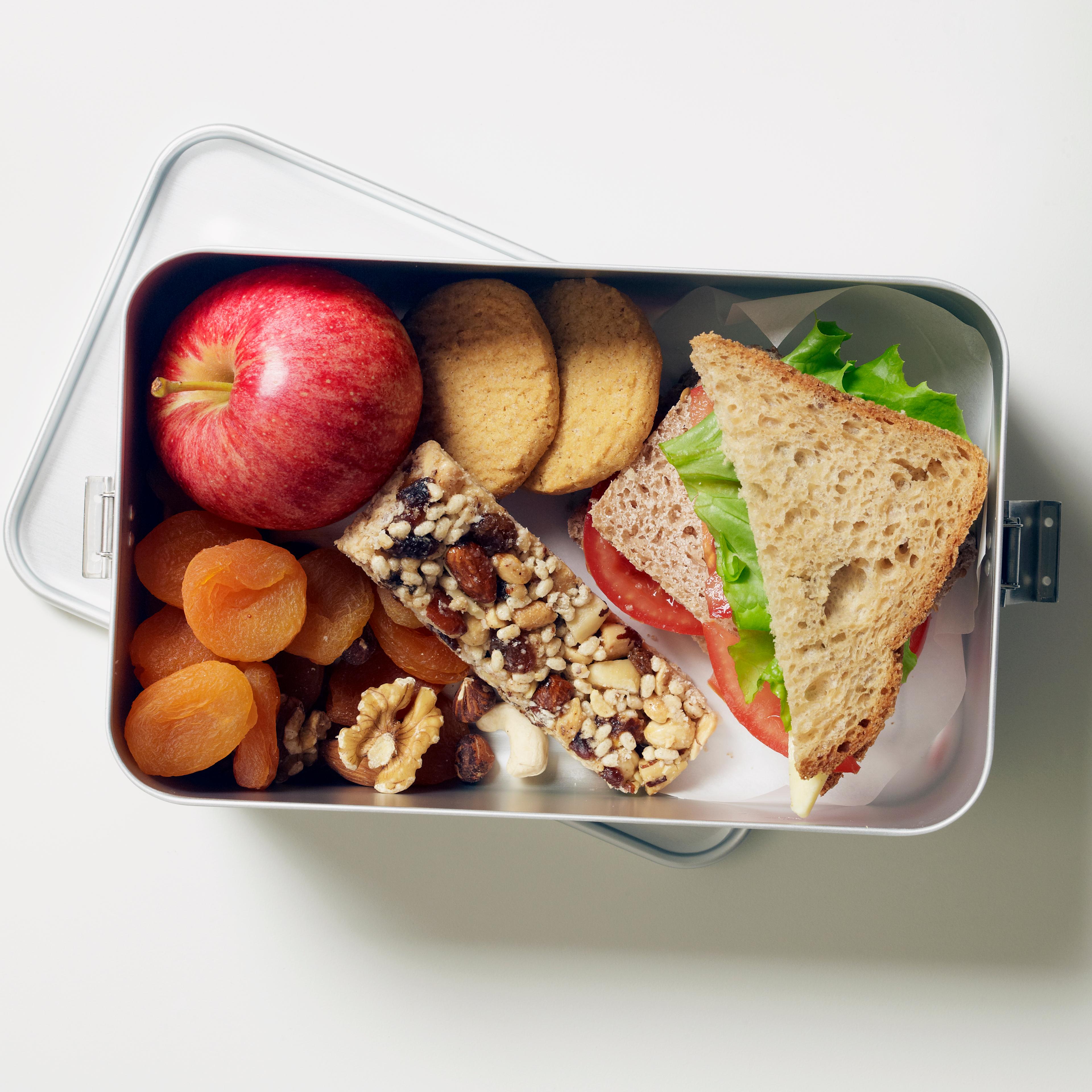 Gluten-free lunch box containing fruit, seed bar, biscuits and sandwiches
