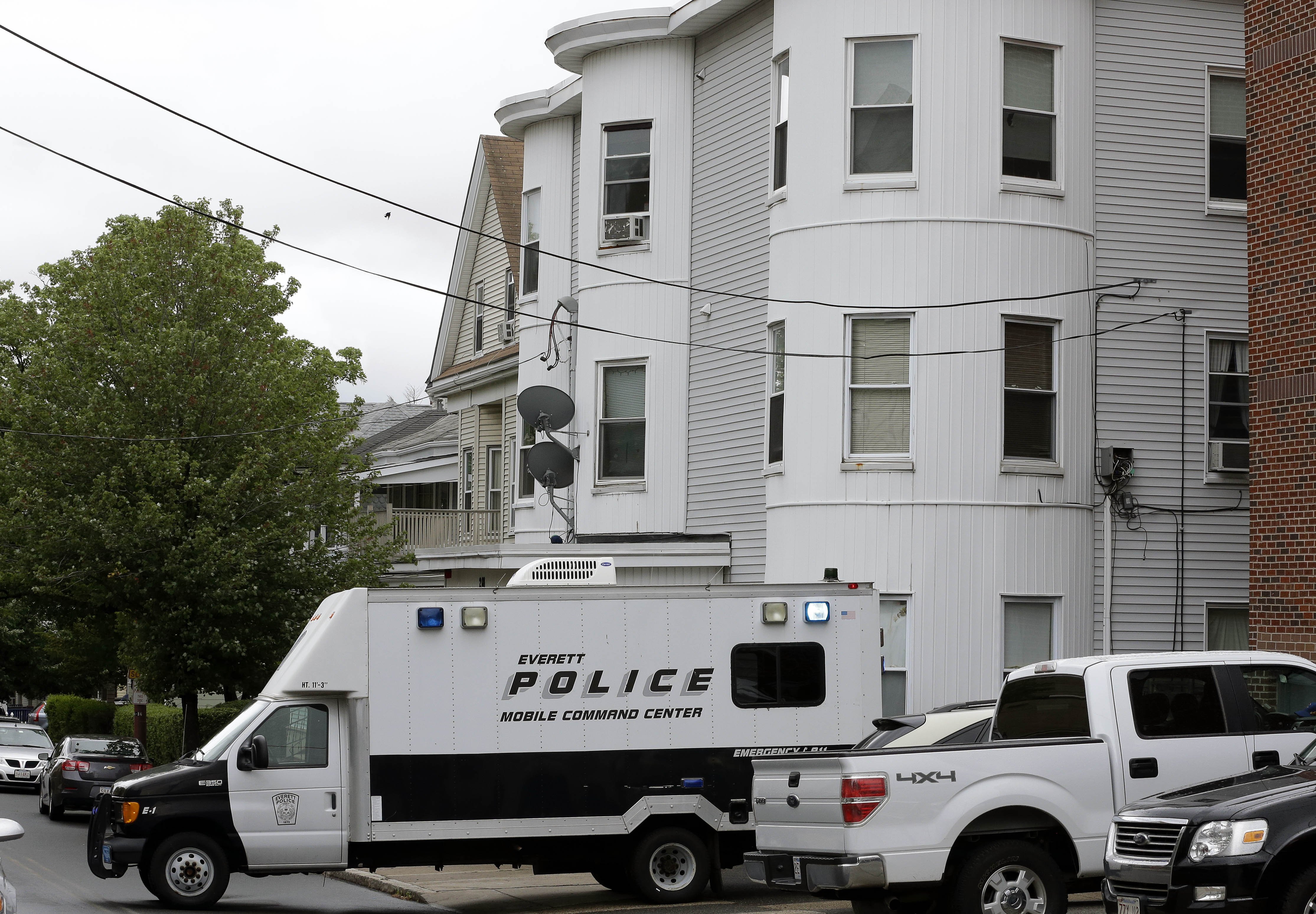 Police vehicles sit in front of a multi-storied home on June 2, 2015, in Everett, Mass., being searched by authorities in connection with a man shot and killed earlier in the day in Boston. The man, under surveillance by terrorism investigators, was kill
