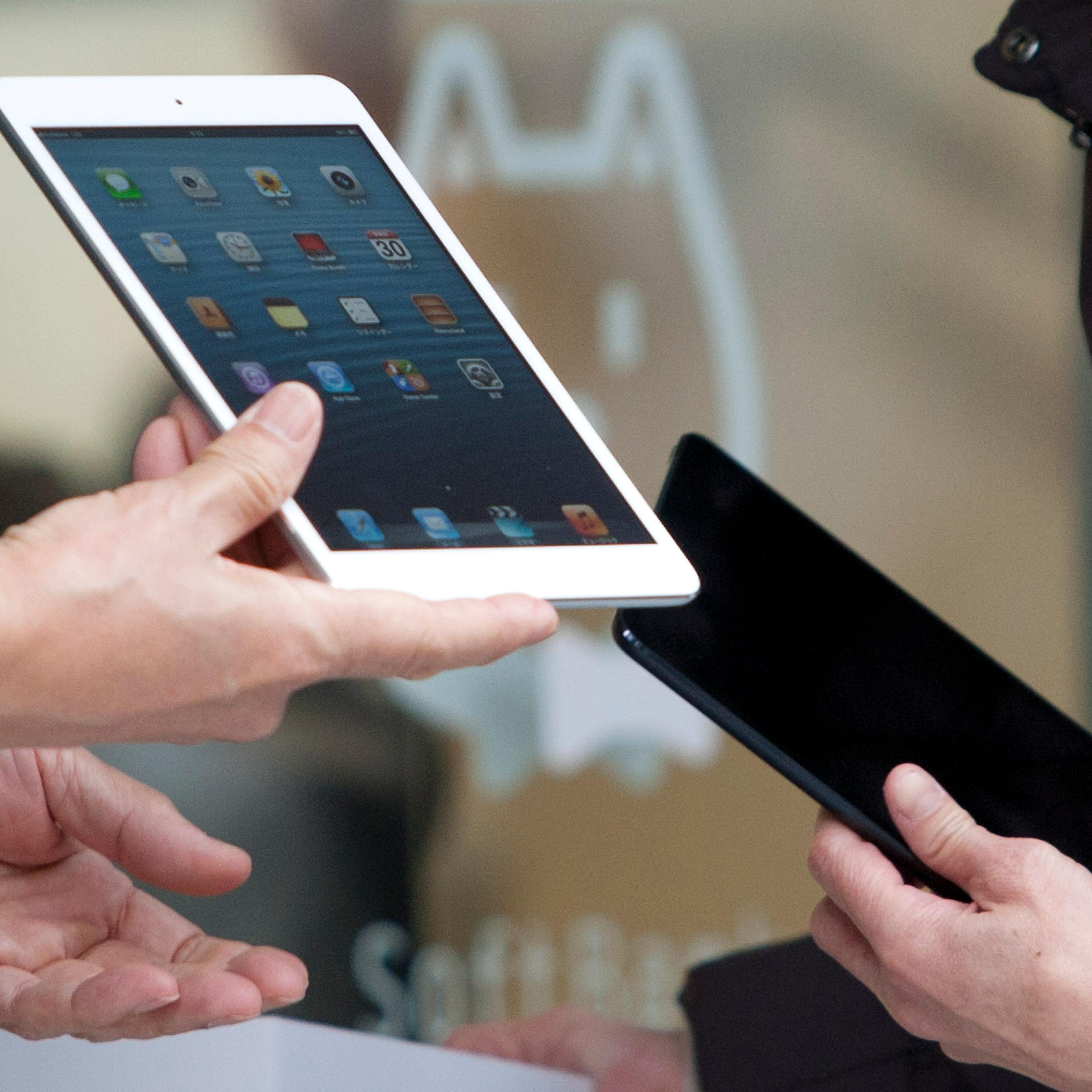 Ken Miyauchi, vice president and chief operating officer of Softbank Corp., left, holds an Apple Inc. iPad Mini during a ceremony as the device goes on sale at the Softbank store in the Ginza district of Tokyo on November 30, 2012.