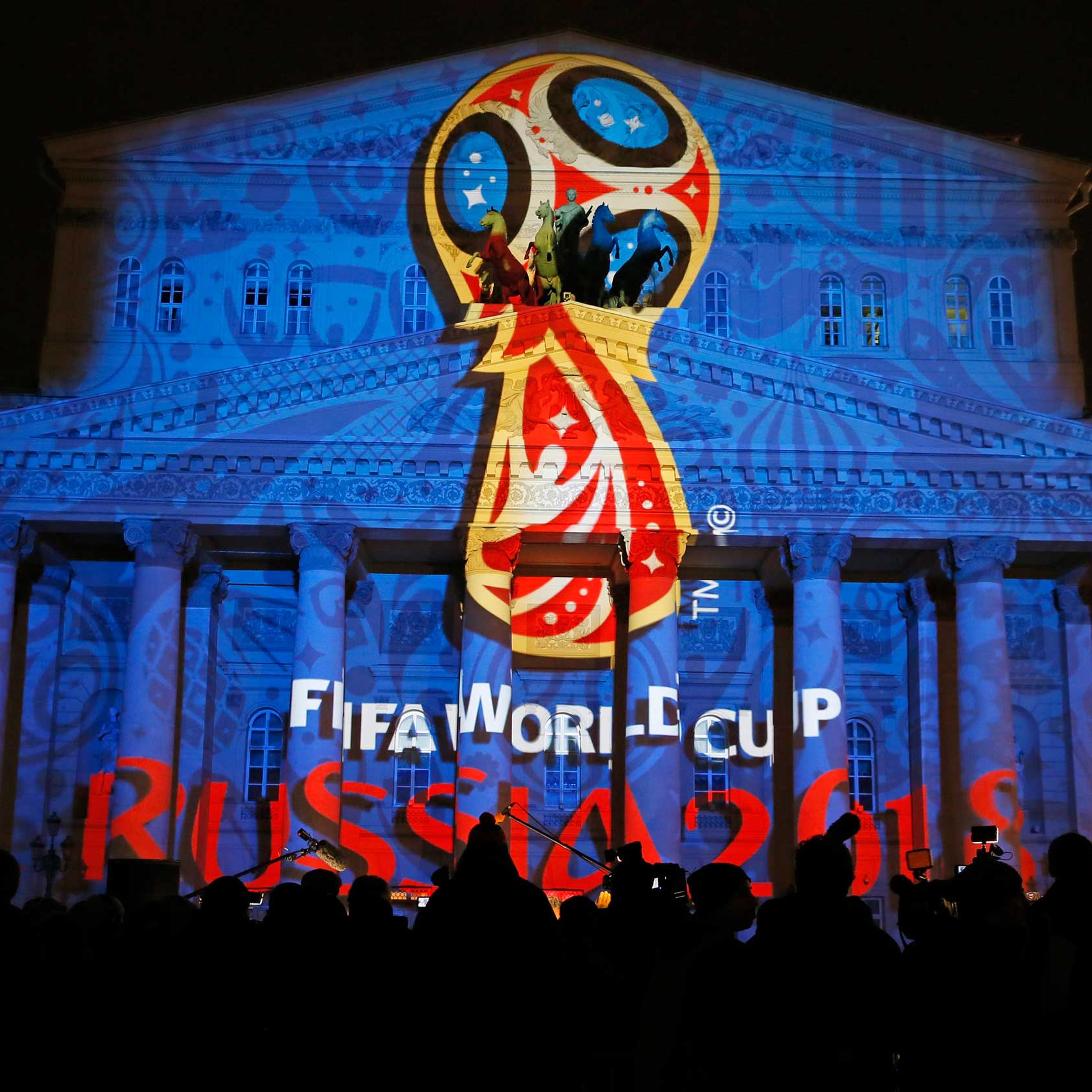 Journalists look at a light installation showing the official logotype of the 2018 FIFA World Cup during its unveiling ceremony at the Bolshoi Theater building in Moscow, October 28, 2014.