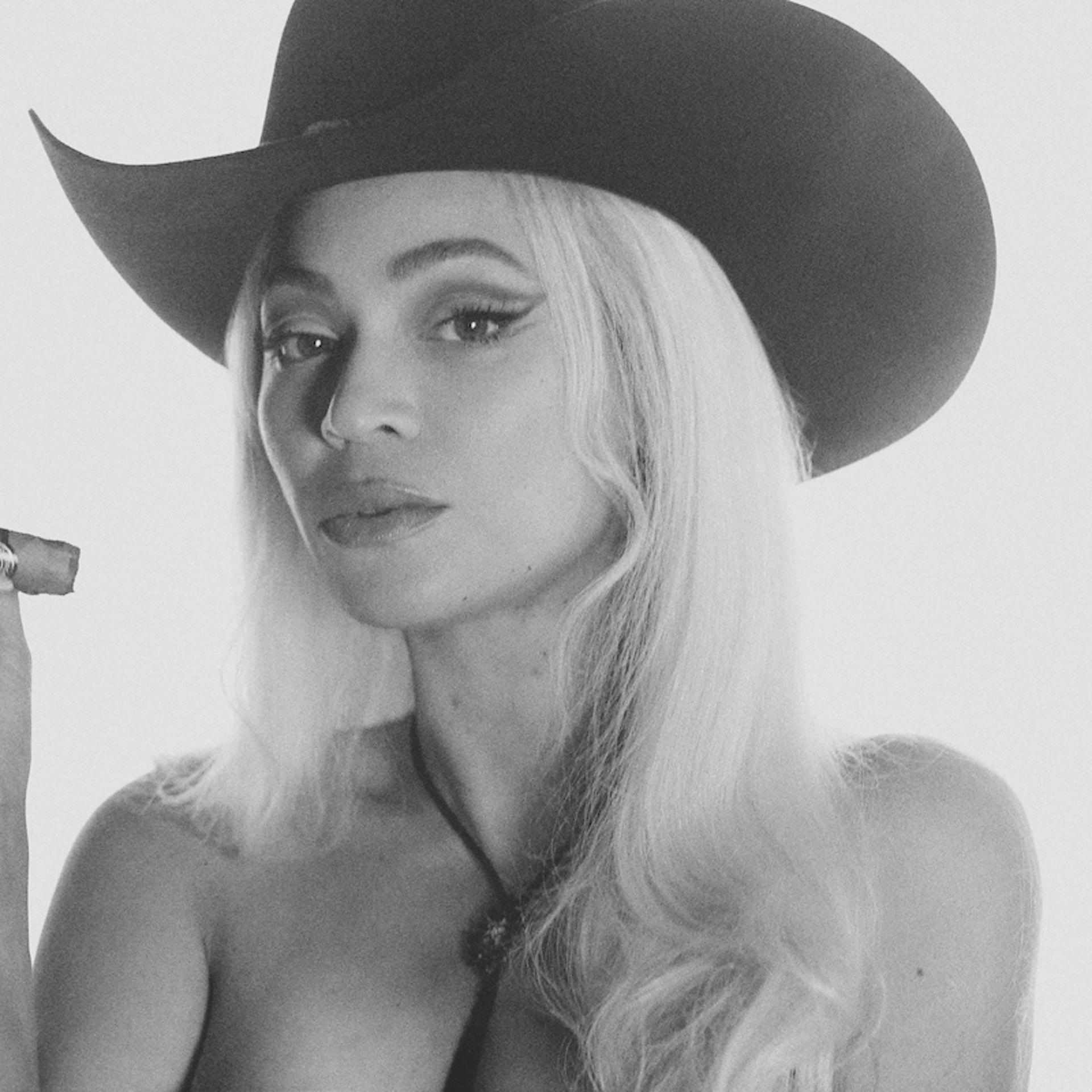 Beyoncé in a cowboy hat smoking a cigar