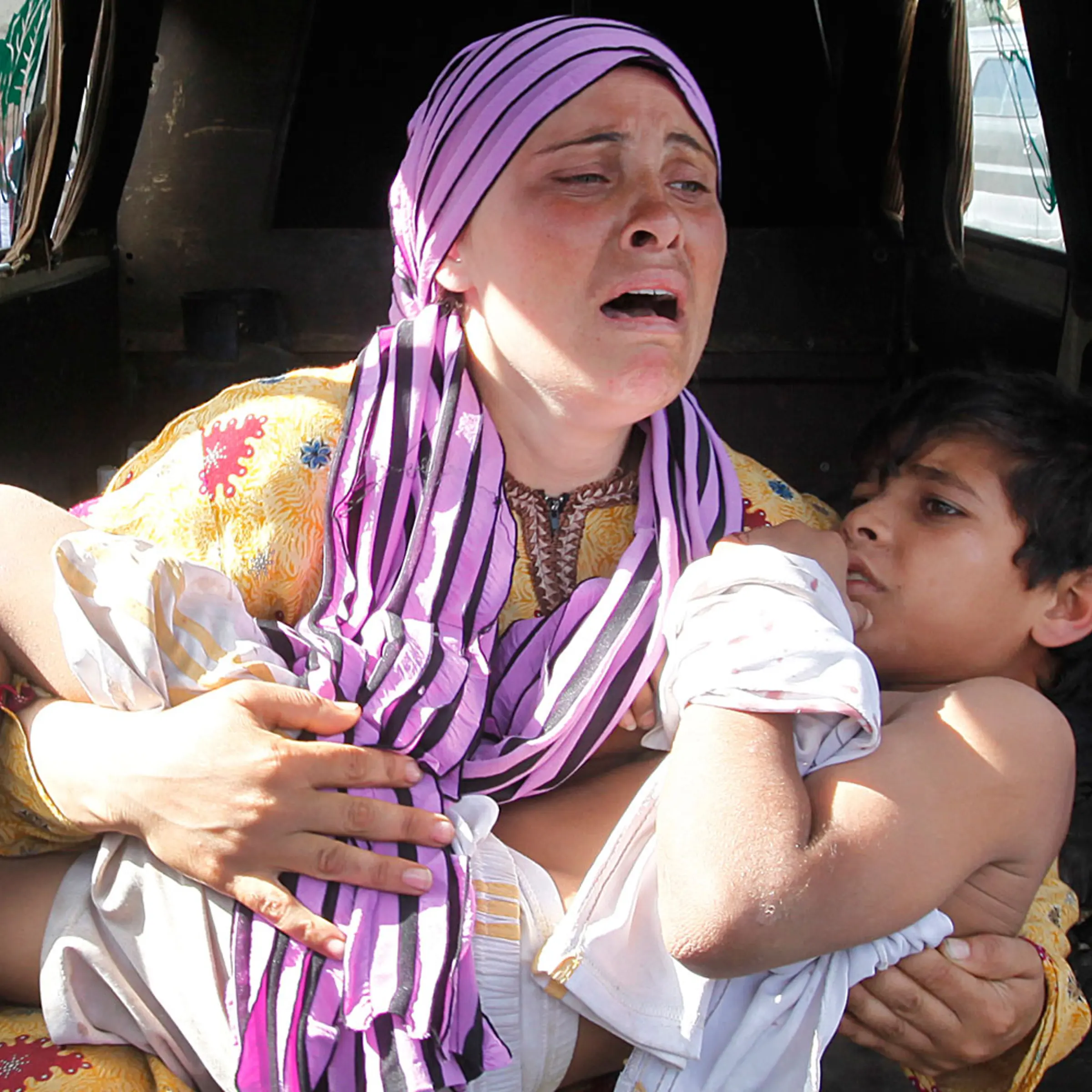 May 30, 2012. A Syrian woman cries as she carries her injured son, who was shot in his hand by the Syrian border guard when they were crossing a river from Syria to Lebanon, at the northern Lebanese-Syrian border town of Wadi Khaled, in Akkar, Lebanon.
