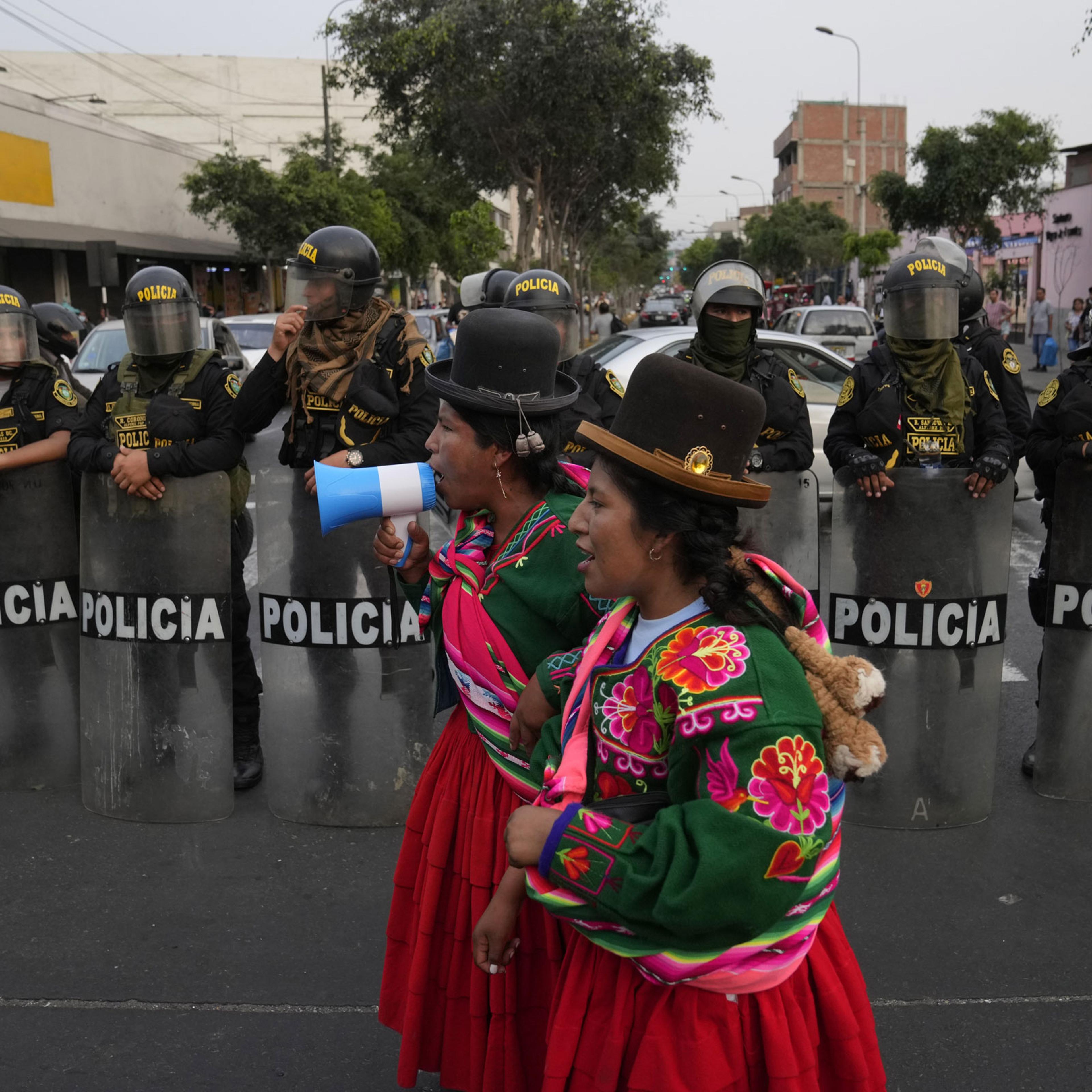 Indigenous anti-government protesters shout in front of a line of police during a march against Peruvian President Dina Boluarte