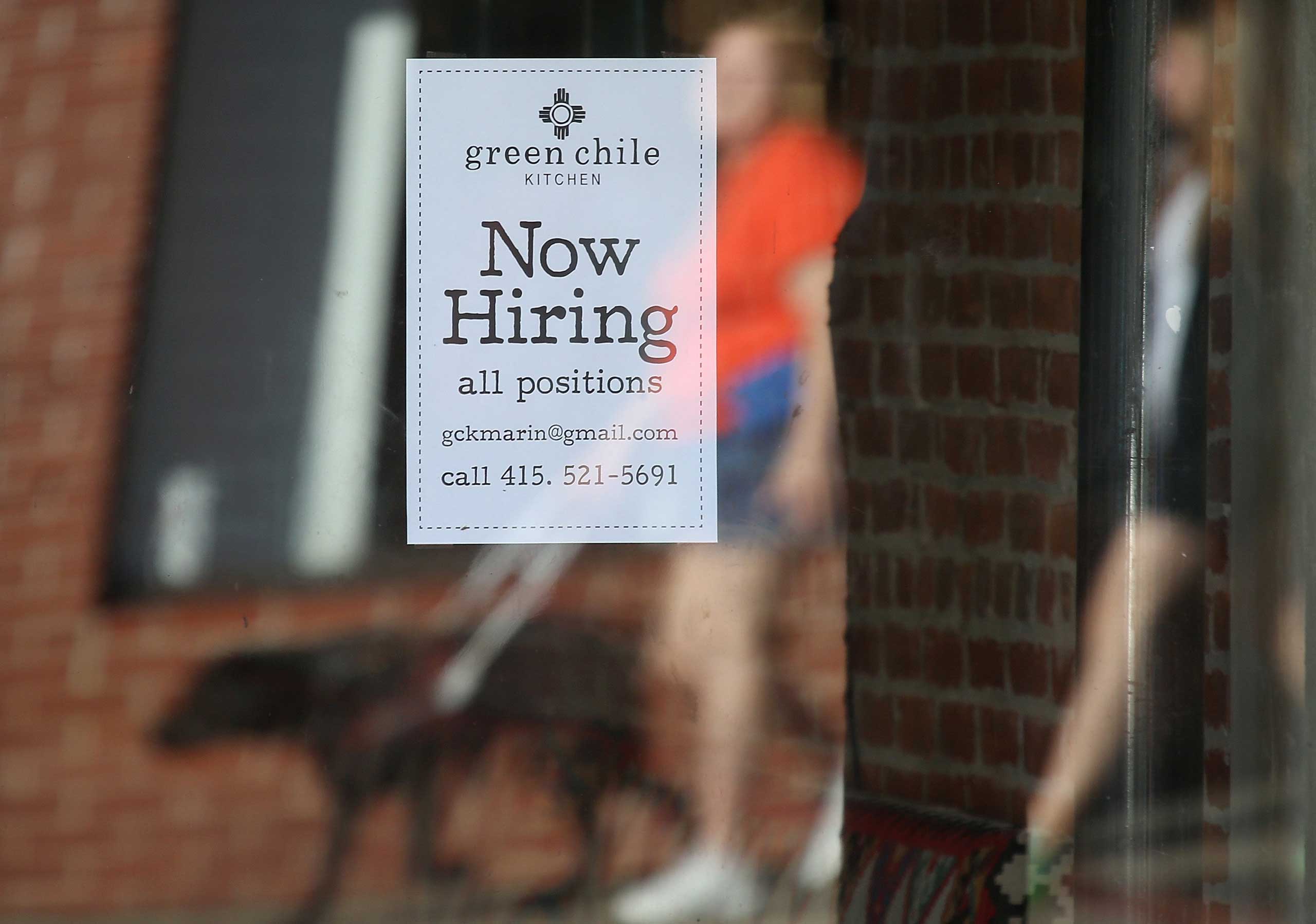 Pedestrians walk by a now hiring sign posted in the window of a business on Nov. 7, 2014 in San Rafael, Calif.