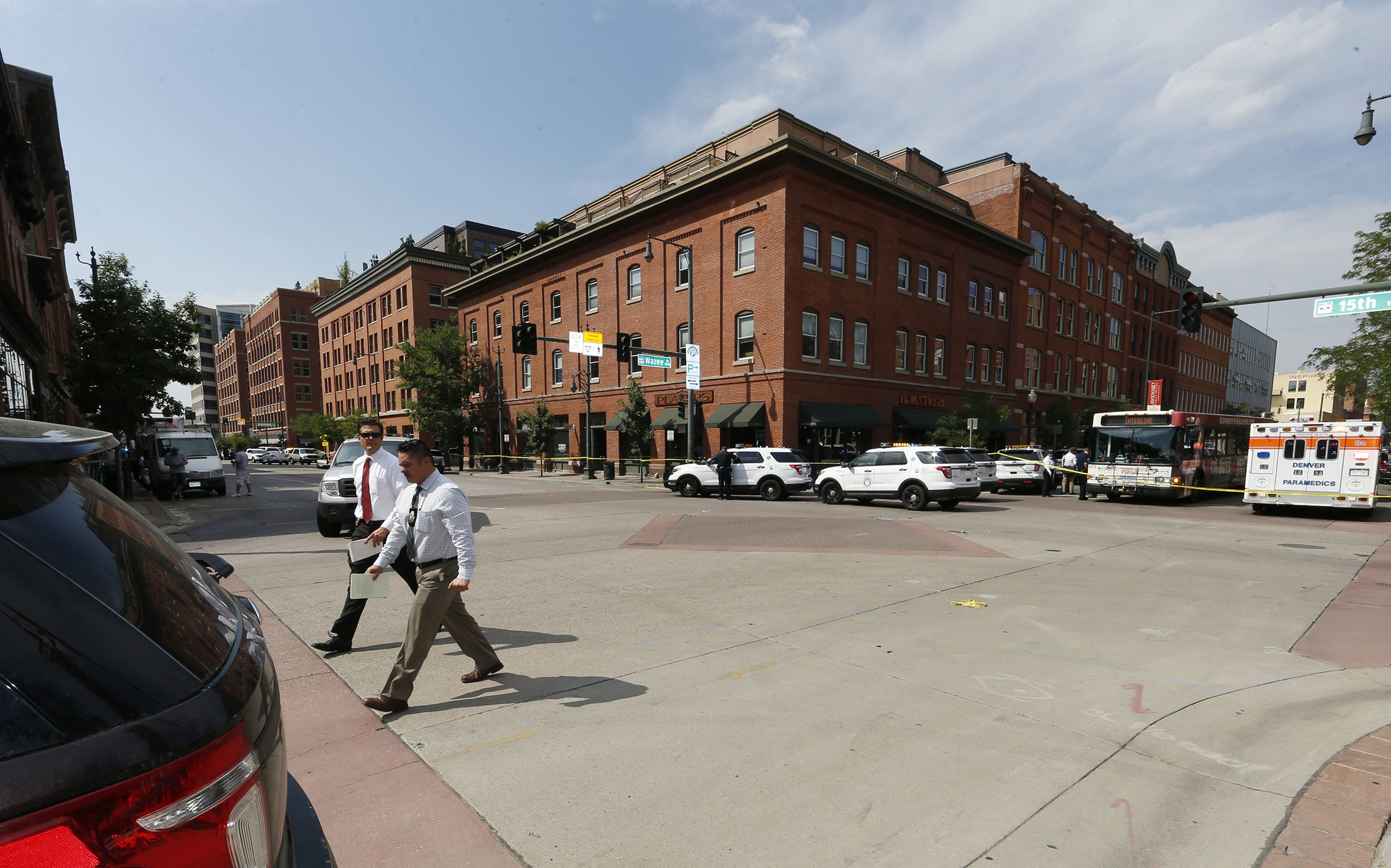 Investigators walk through the intersection of 15th Street and Wazee near the scene of a shooting in a lower downtown business in Denver on June 28, 2016.