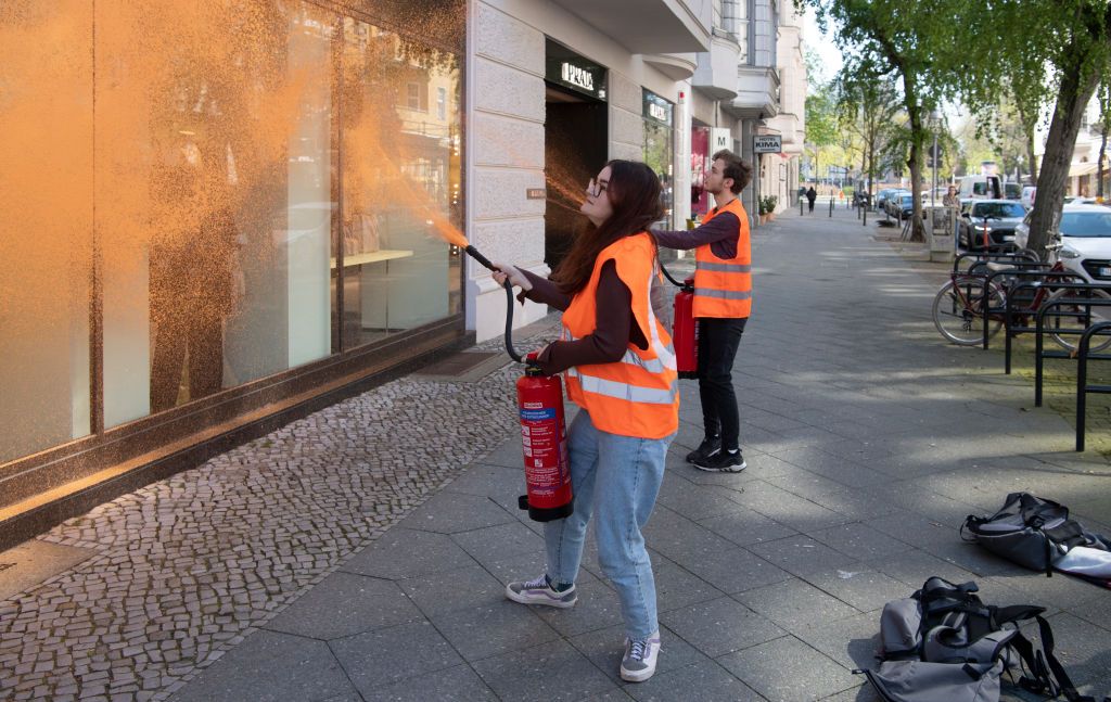 22 April 2023, Berlin: Activists from the environmental group Letzte Generation spray a facade of a luxury store. "The richest Germans emit a thousand times as many greenhouse gases as the average. While the ordinary people have to bear the consequences,