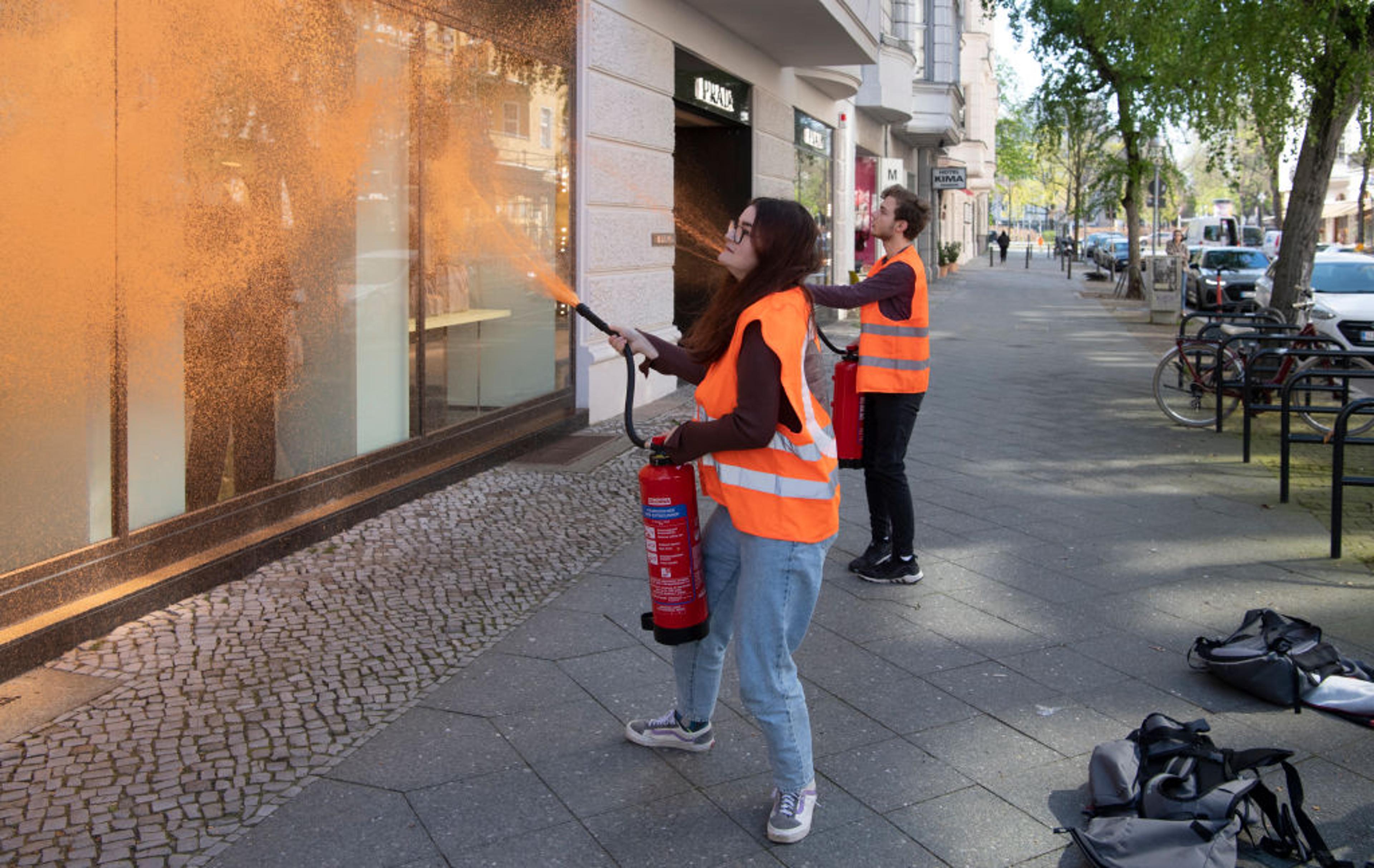 22 April 2023, Berlin: Activists from the environmental group Letzte Generation spray a facade of a luxury store. "The richest Germans emit a thousand times as many greenhouse gases as the average. While the ordinary people have to bear the consequences,
