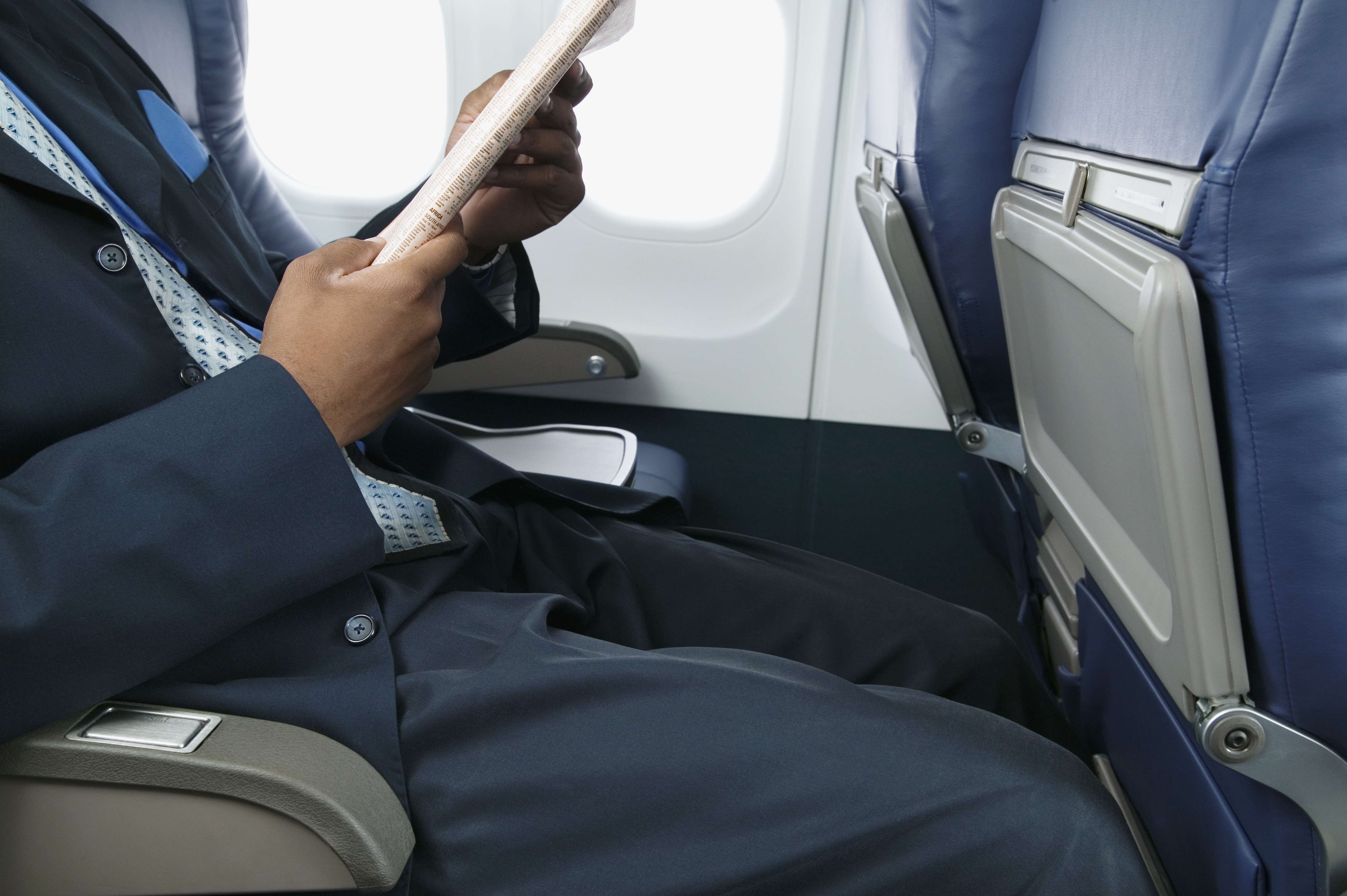 Businessman reading a magazine sitting in an airplane