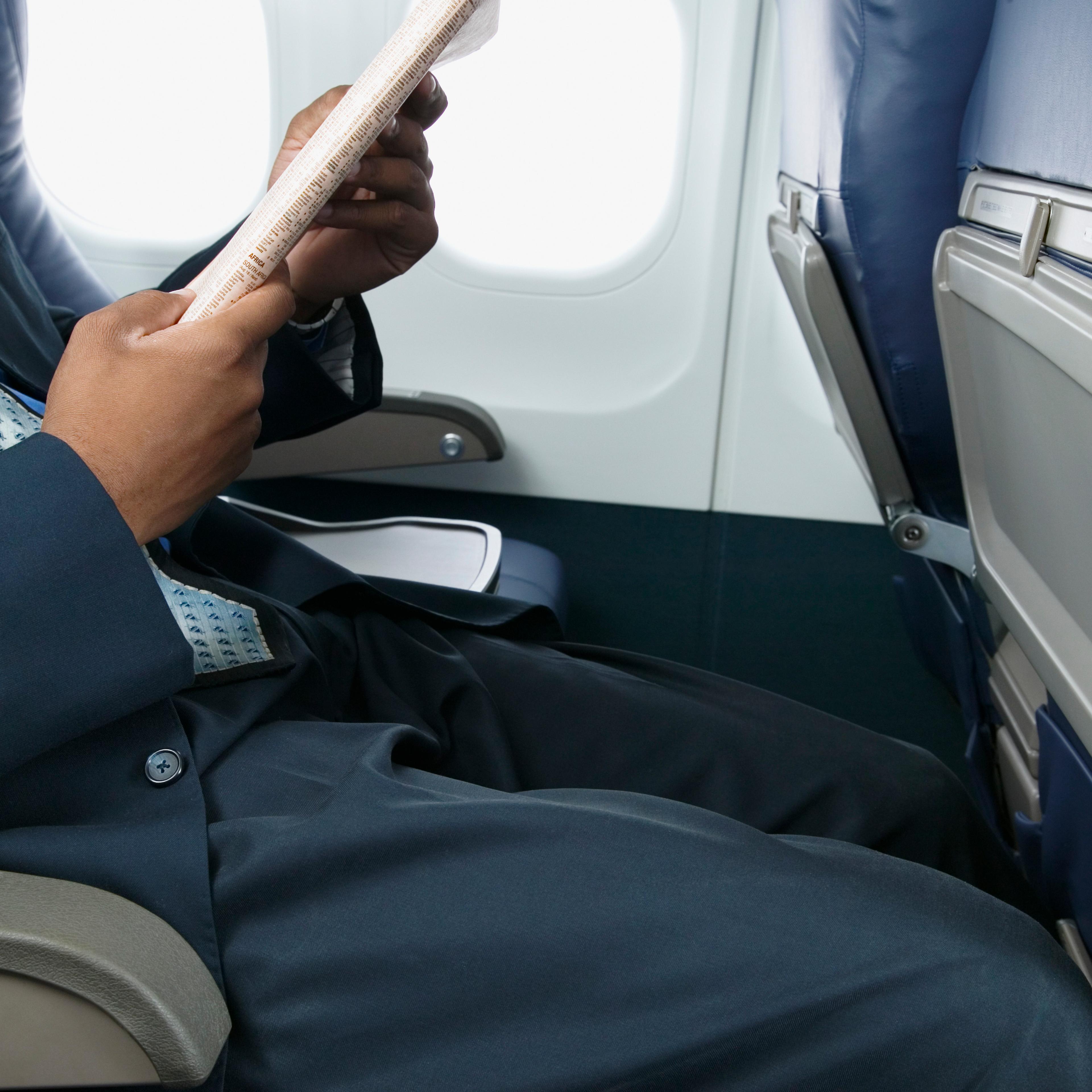 Businessman reading a magazine sitting in an airplane