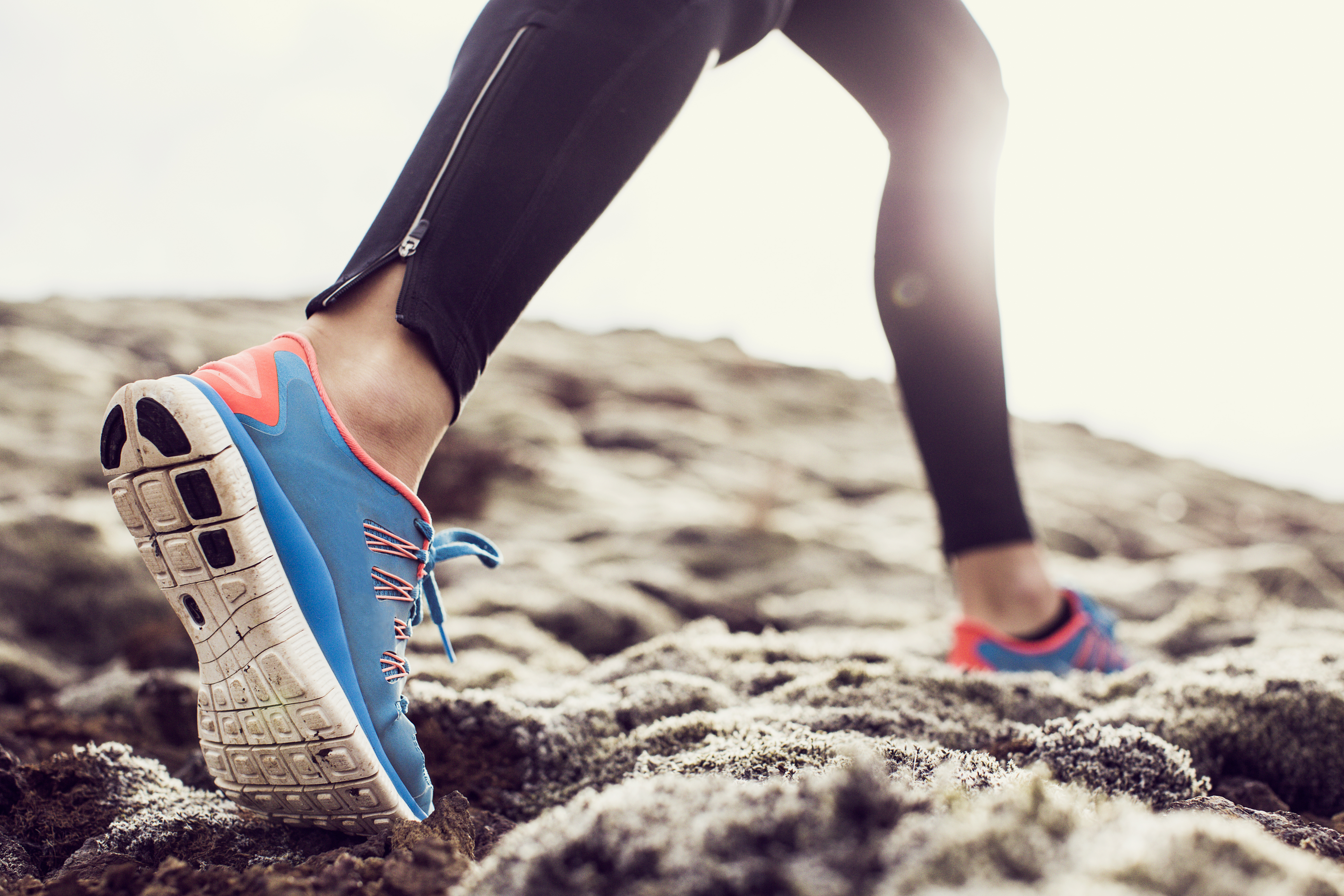 Close up of trainers running through mossy terrain