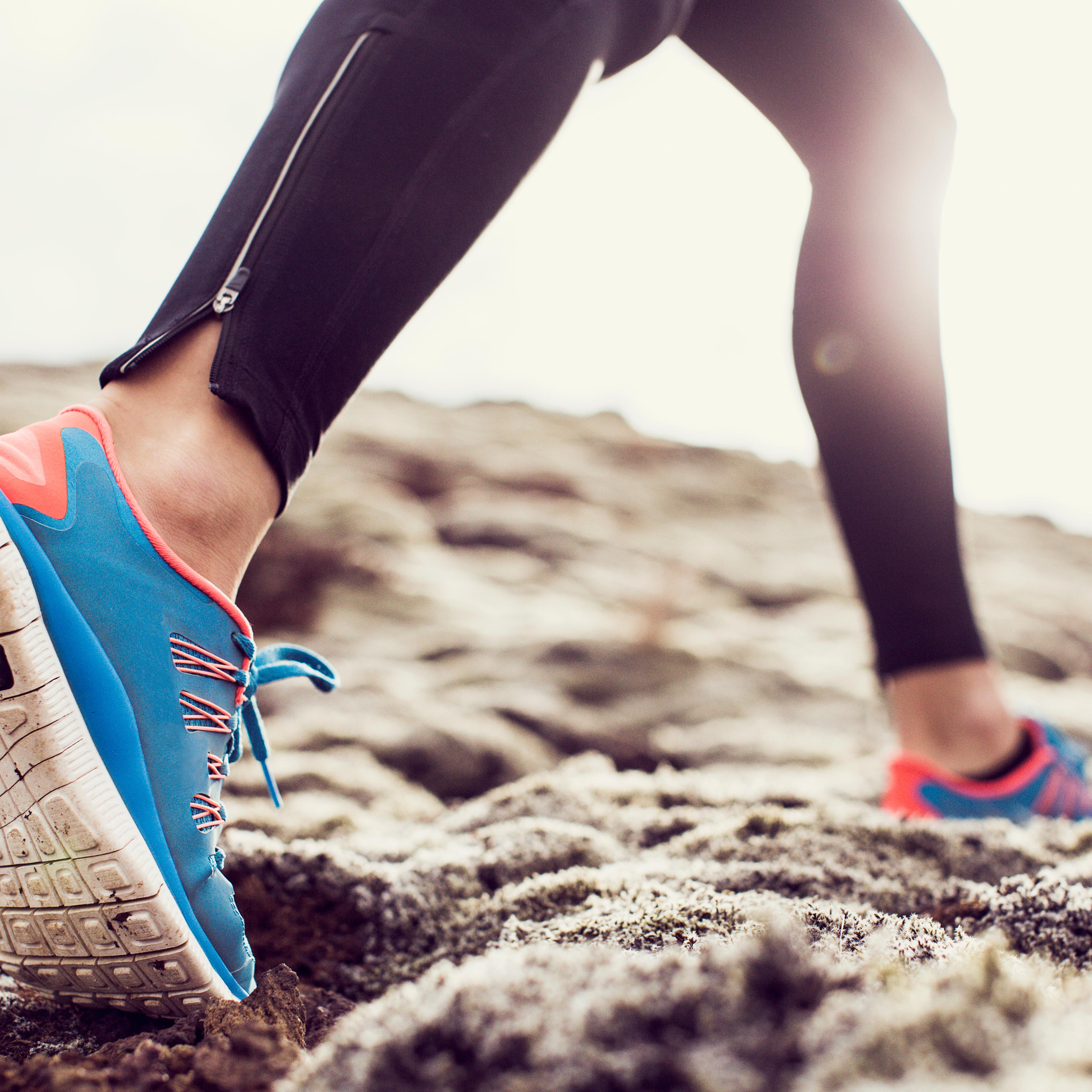 Close up of trainers running through mossy terrain