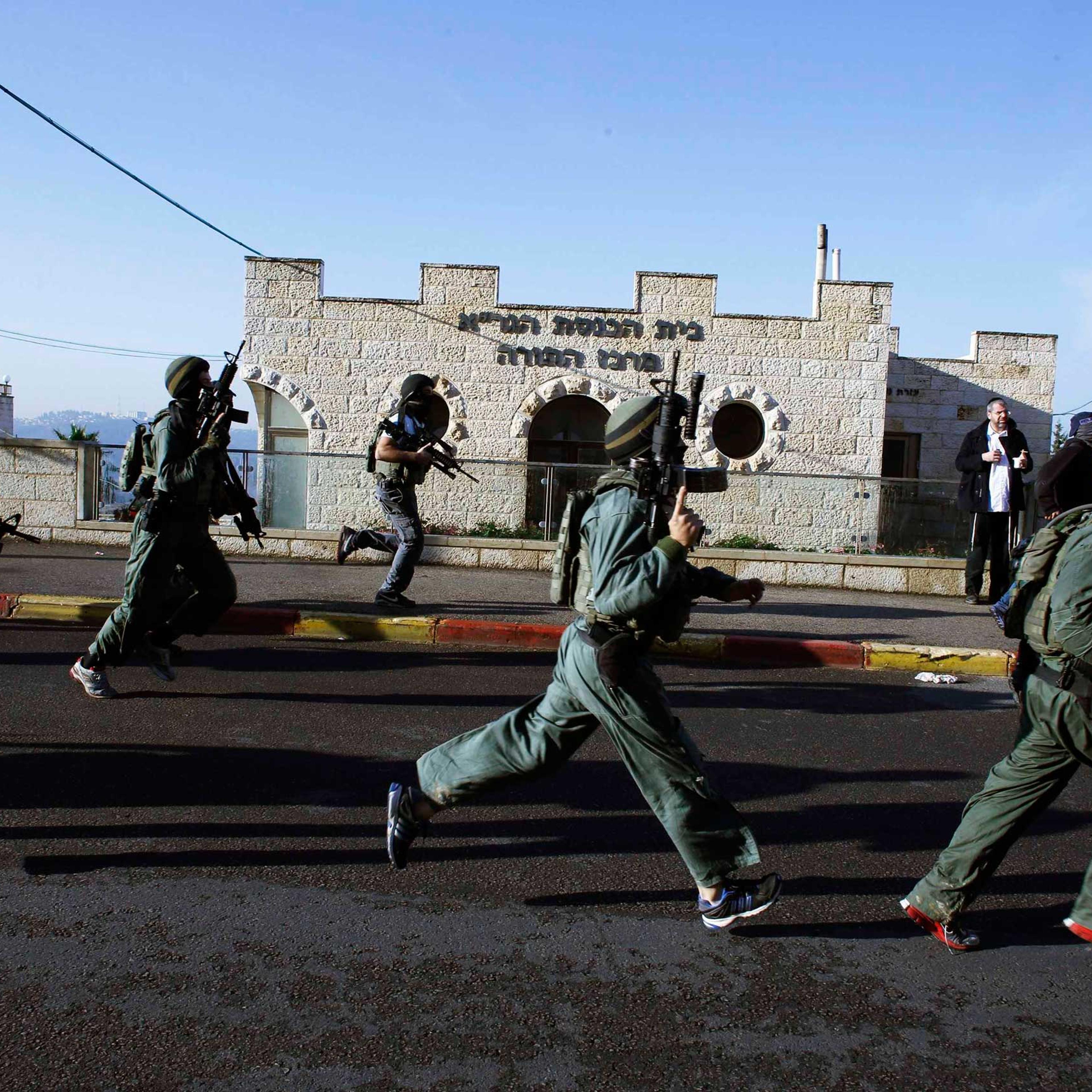 Israeli security personnel run next to a synagogue, where a suspected Palestinian attack took place, in Jerusalem, Nov. 18, 2014.
