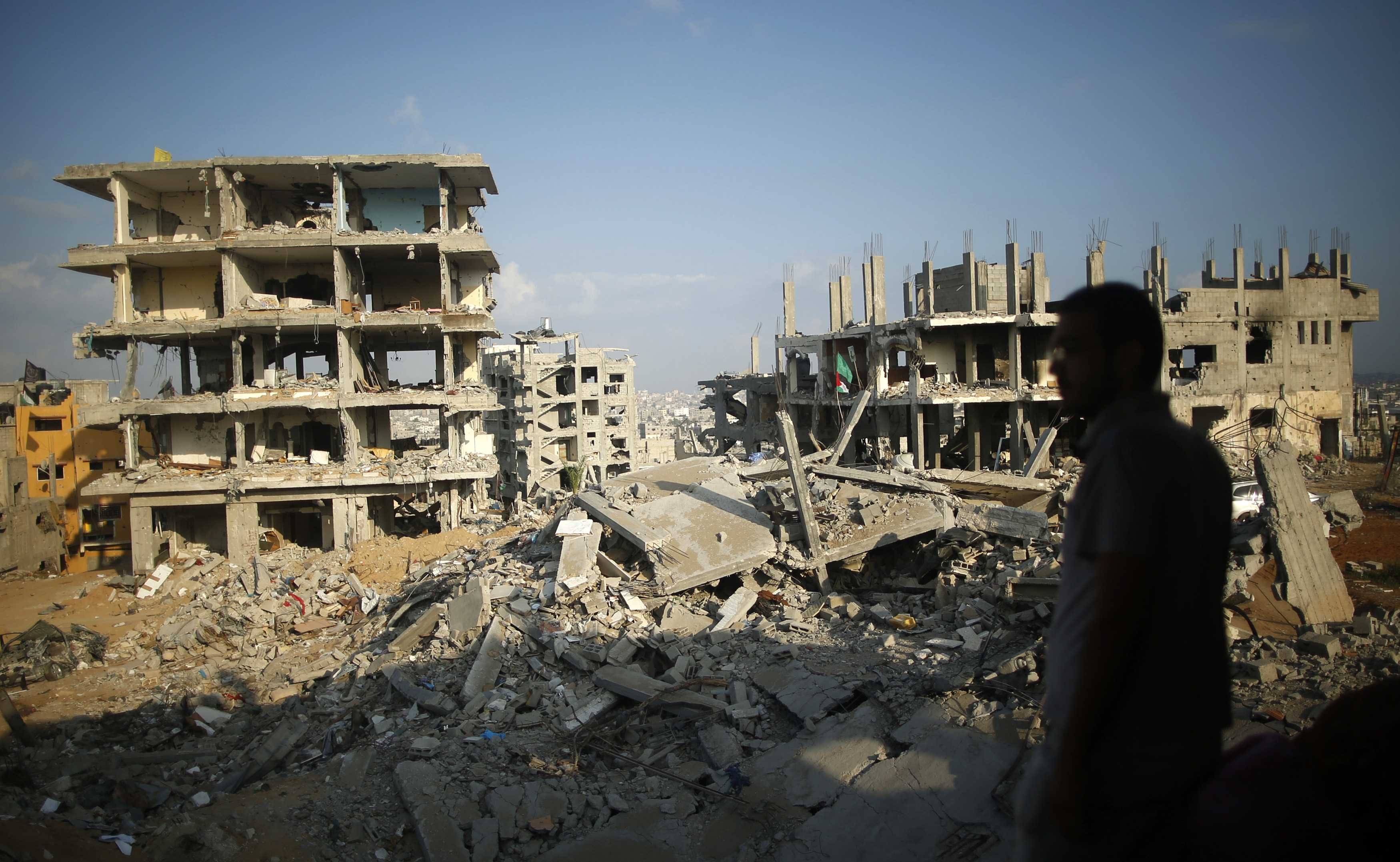 A Palestinian man stands atop the rubble of his house as he looks at the ruins of his neighborhood that was badly damaged during the 50-day war between the Hamas militant movement and Israel, in the east of Gaza City on Oct. 12, 2014.