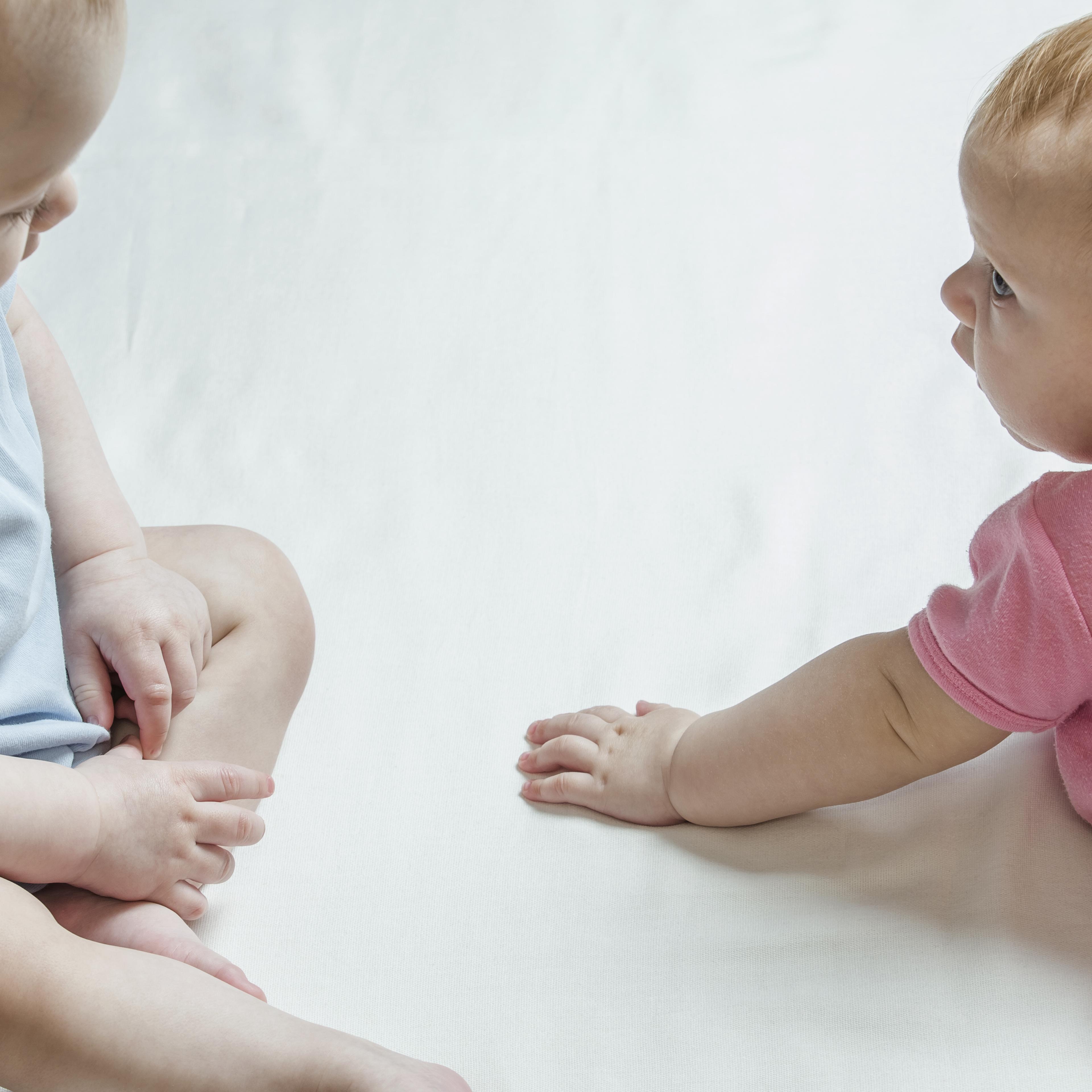 Two babies looking at each other curiously