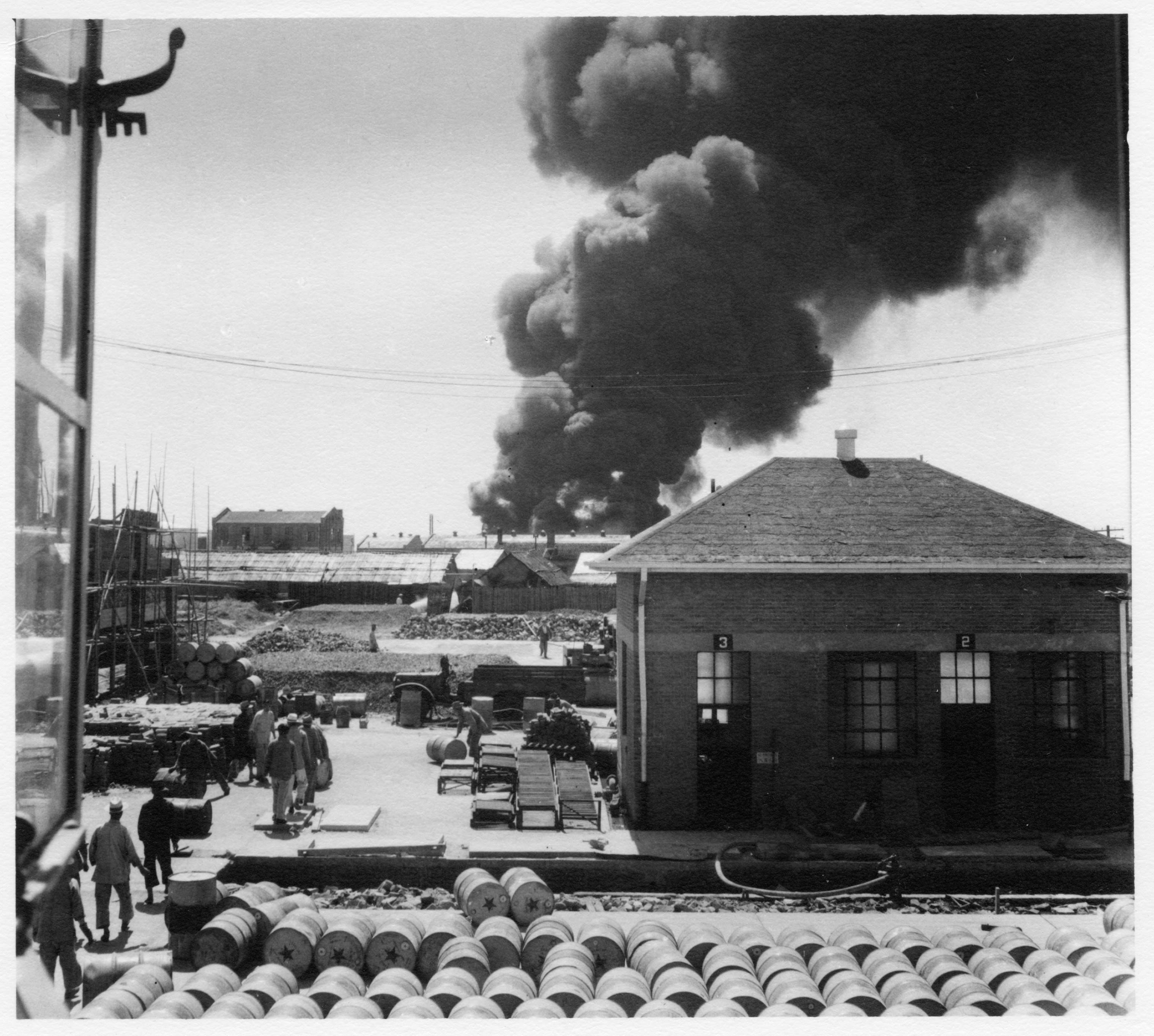 Smoke rises from the neighboring Standard Vacuum Oil Terminal where the heaviest fighting took place.