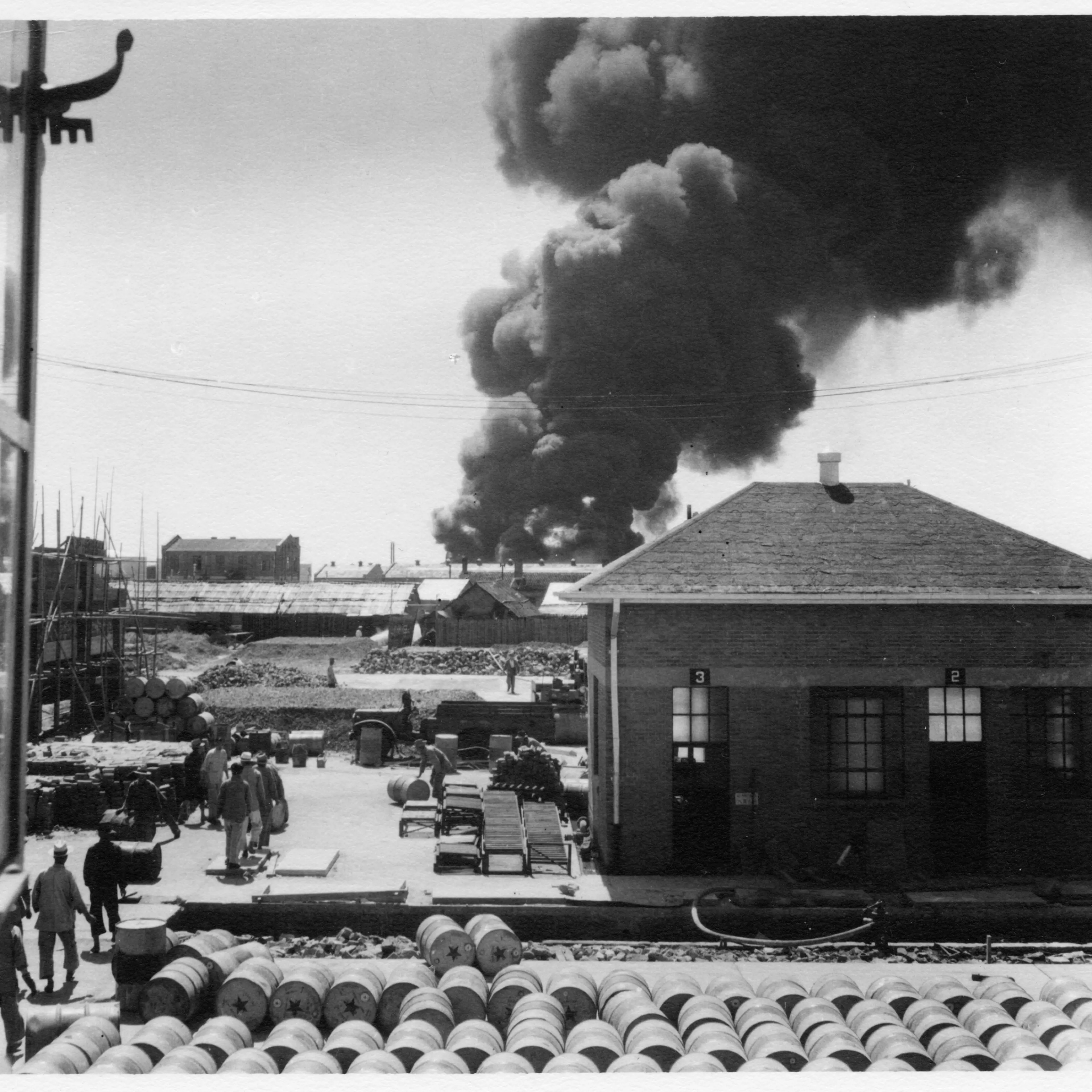 Smoke rises from the neighboring Standard Vacuum Oil Terminal where the heaviest fighting took place.