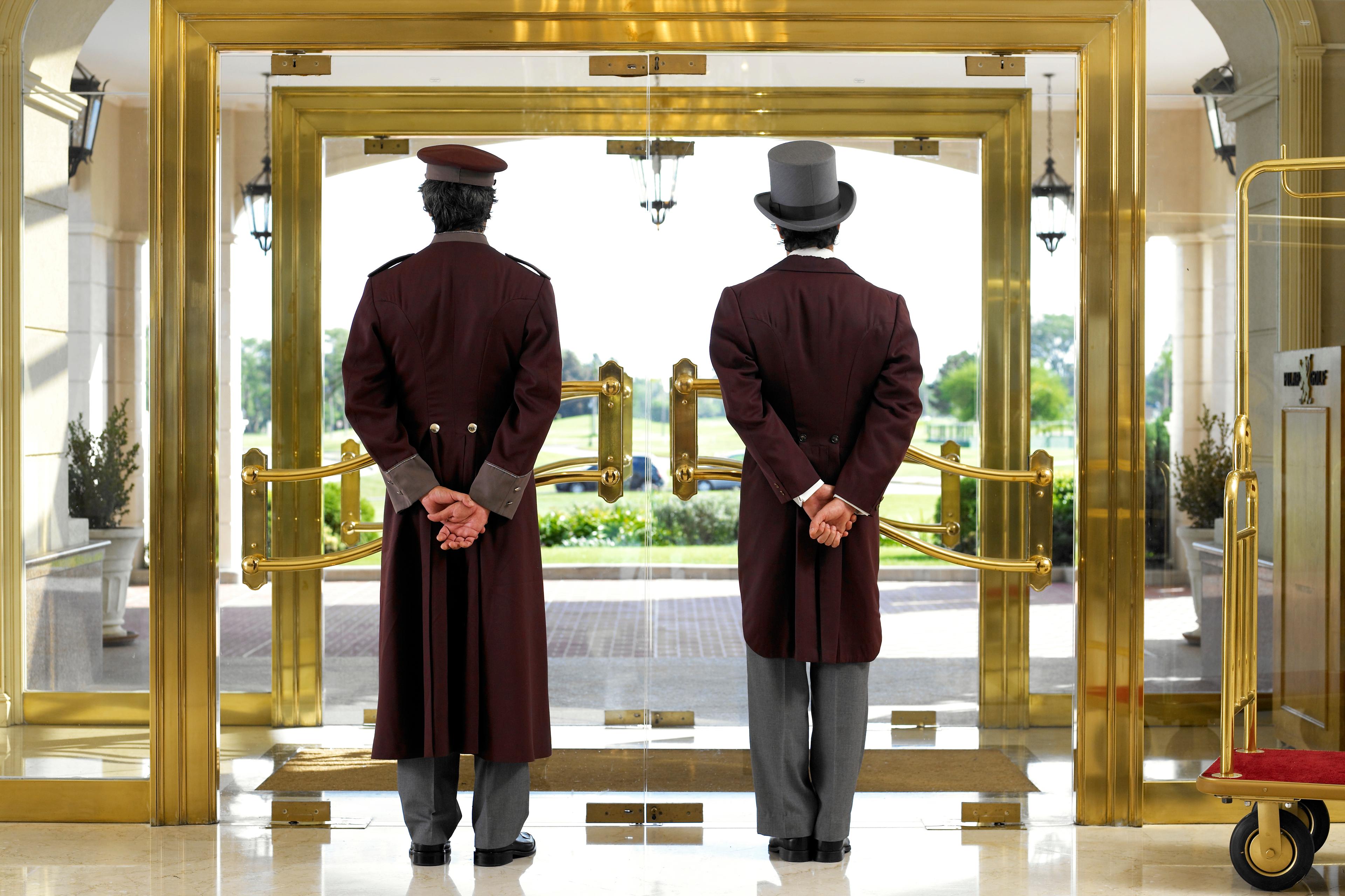 Concierge and bellboy standing at hotel entrance